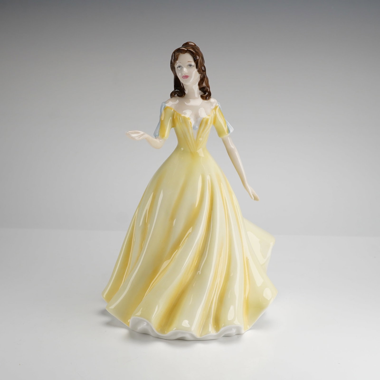 Royal Doulton Classics Figurine Georgia HN 4457: A Royal Doulton bone china figurine titled Georgia, model HN 4457, from the Classics collection. This hand decorated piece depicts a woman in a pale yellow gown with blue tinted sleeves and brown hair