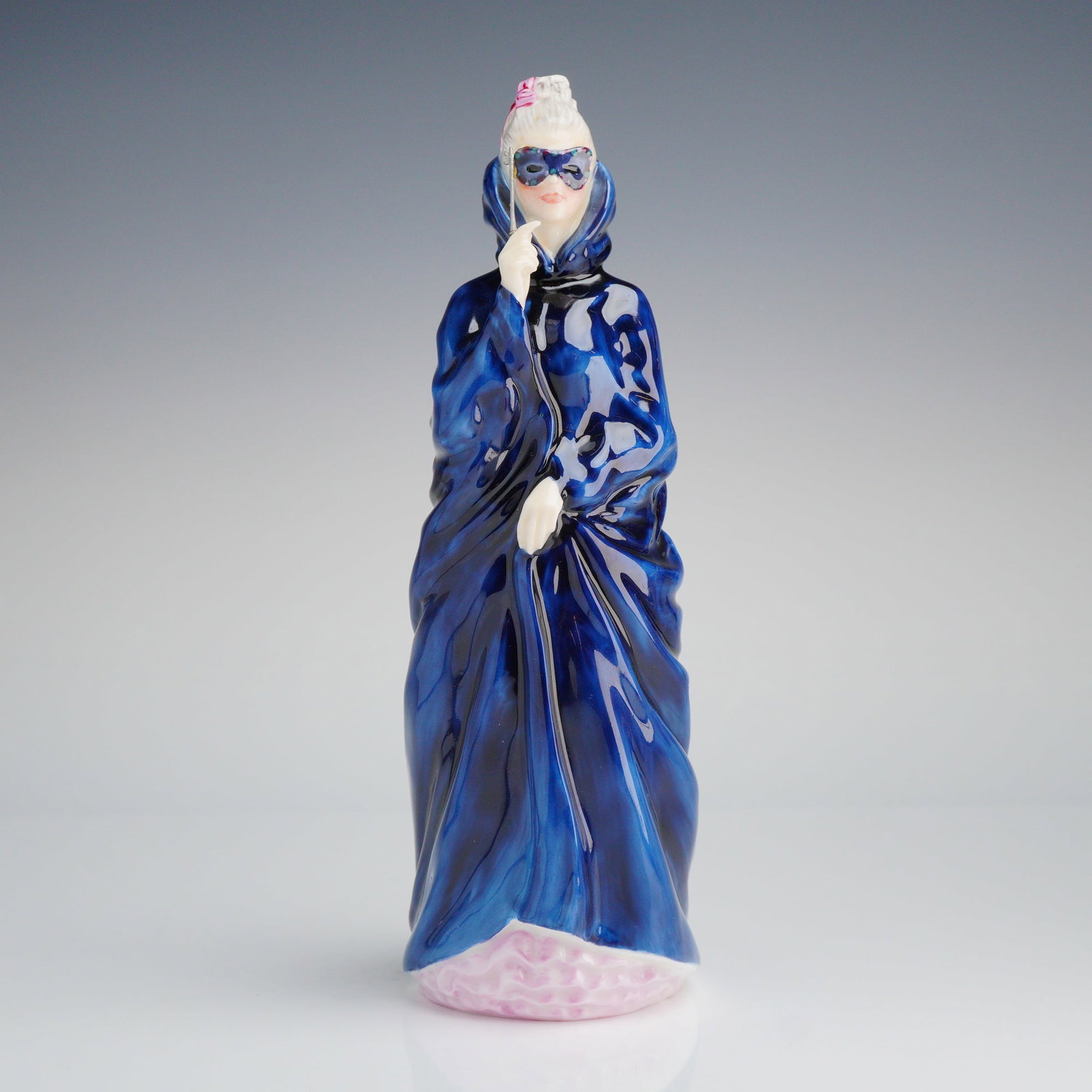 Royal Doulton Figurine, Masque HN 2554: A Royal Doulton figurine, depicting a woman in a predominantly blue flowing cloak and mask, marked underneath with the Royal Doulton backstamp and dated 1972. Dimensions: 3.75"L x 3.00"W x 8.75"H Weig