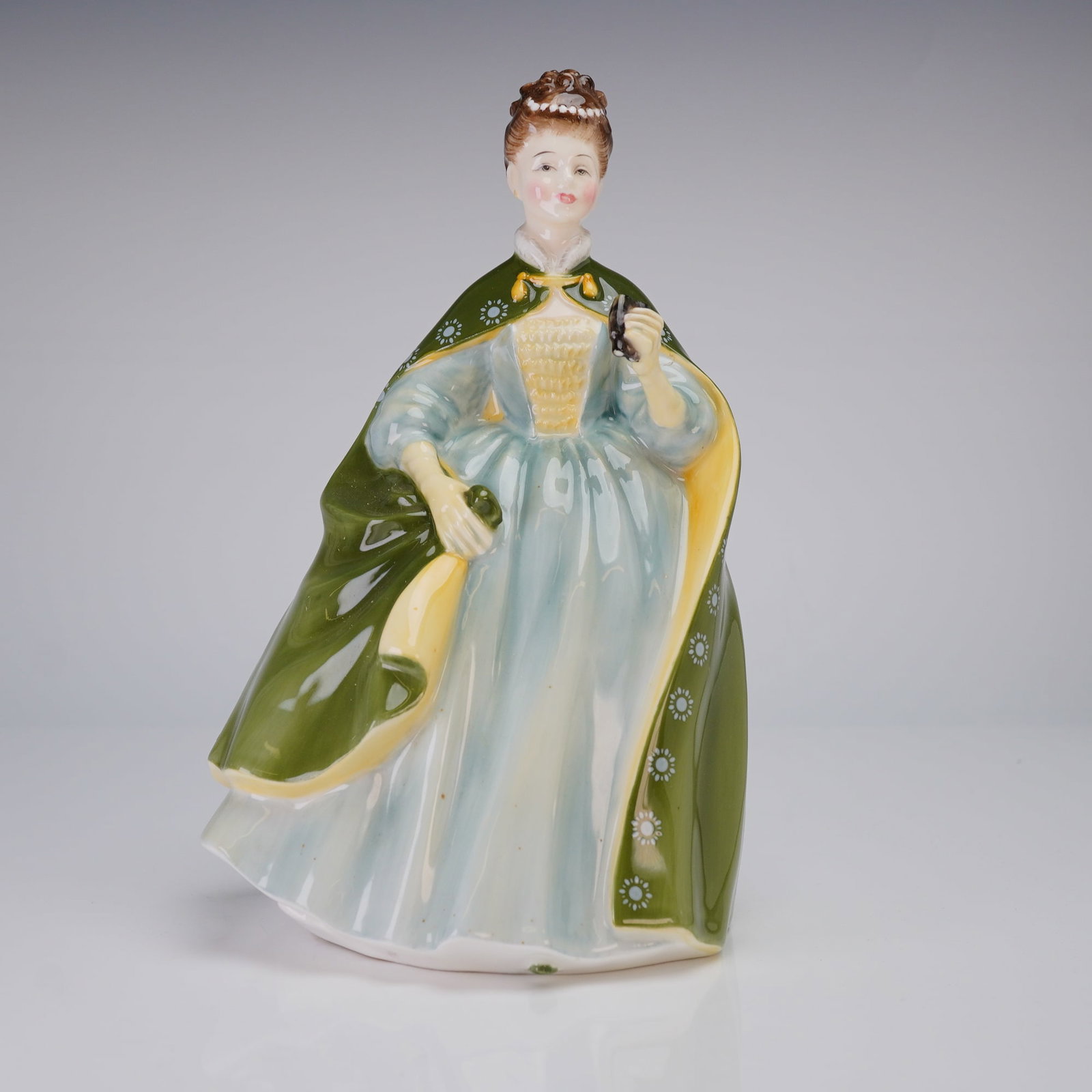 Royal Doulton Figurine Premiere HN2343: A Royal Doulton porcelain figurine, featuring a woman in a green and light blue dress and cloak, marked on the base with the Royal Doulton crown logo. Dimensions: 5.00"L x 4.50"W x 7.75"H Weight: 1.00