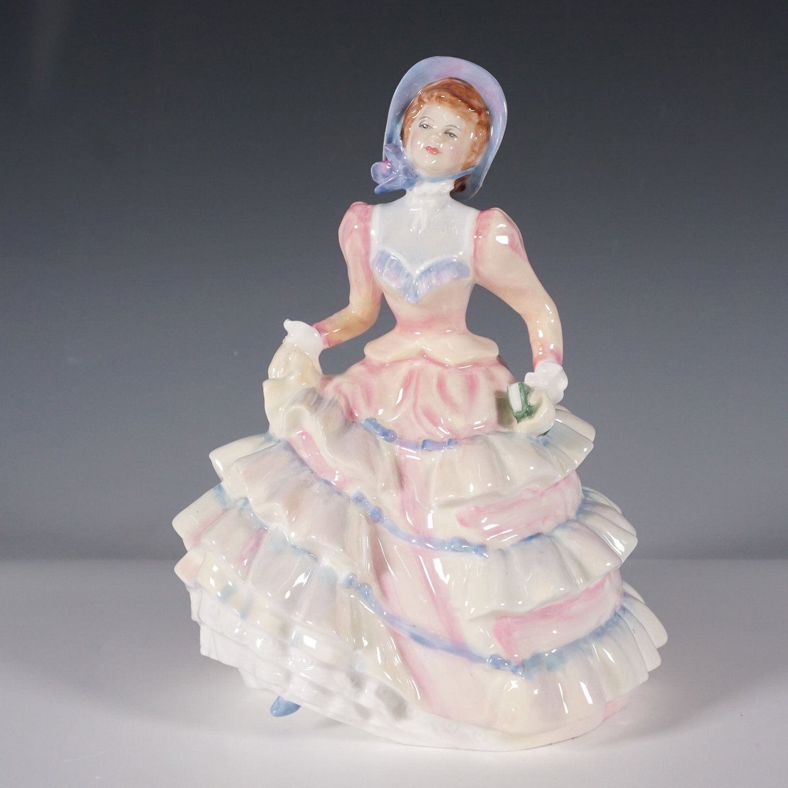 Royal Doulton Porcelain Figurine Hannah HN3369: This Royal Doulton figurine, titled Hannah (HN3369), was designed by Nada Pedley and issued between 1991 and 1996. It features a graceful lady in a flowing pale pink gown with yellow and blue accents,