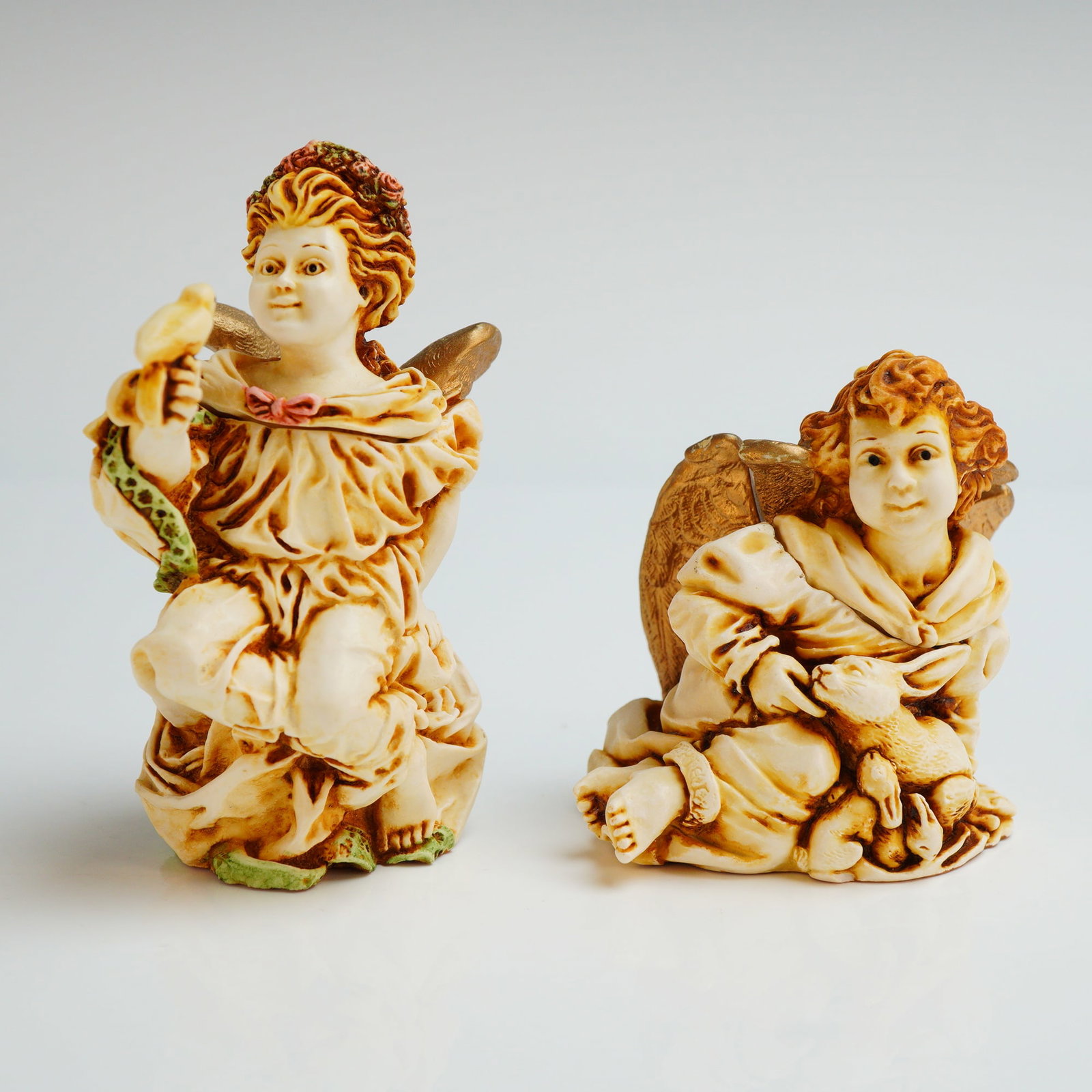 2pc Harmony Kingdom Trinket Boxes, Joie De Vivre and La Gardienne: The box titled La Gardienne (ANSE98) , depicts a winged cherub with a floral crown holding a small bird. The figurine titled Joie De Vivre (ANJO) , depicts a winged cherub holding a rabbit. Both items