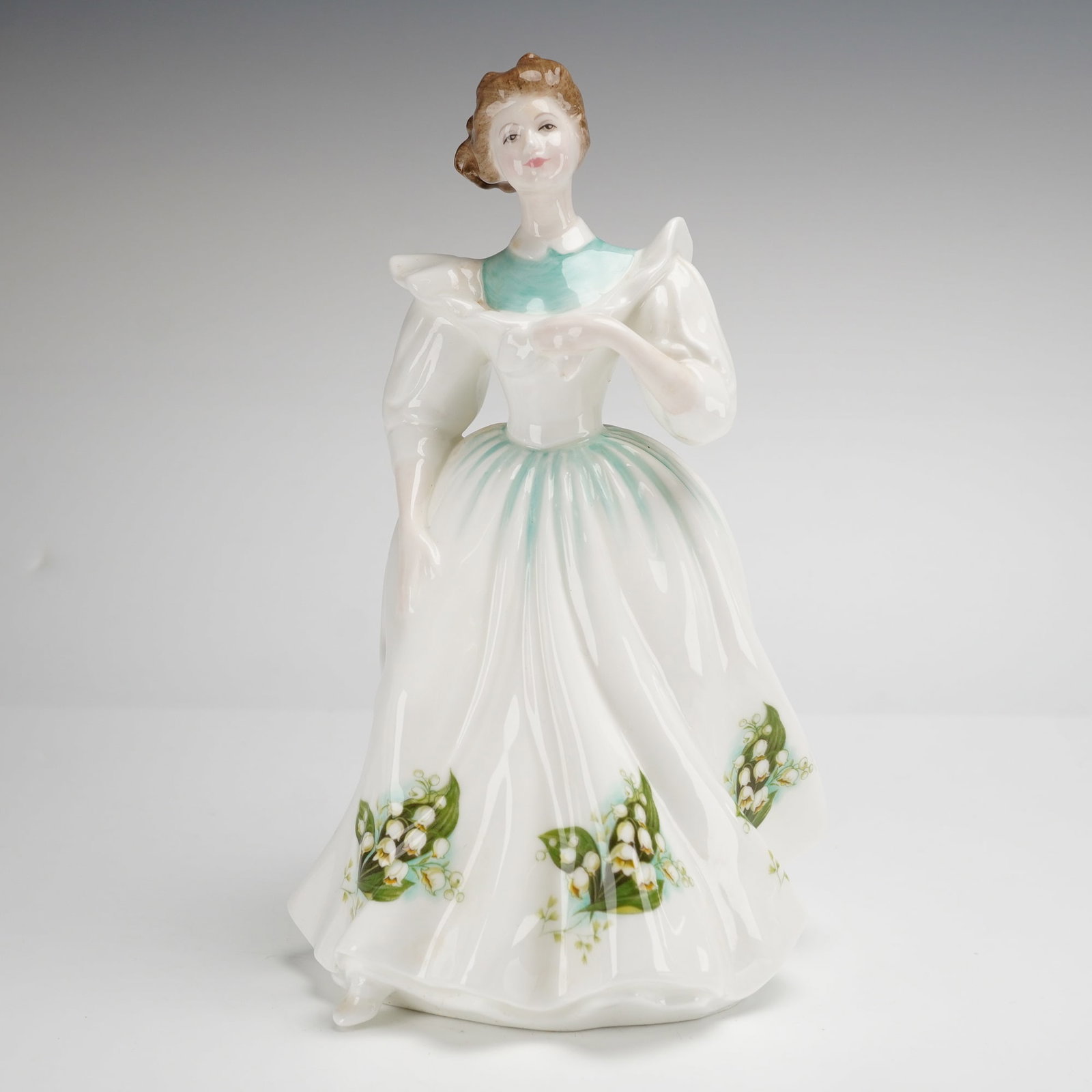 Royal Doulton Bone China Figurine May HN2711 Figure of the Month: A Royal Doulton bone china figurine titled May HN2711 from the Figure of the Month series. Modeled by designer Peggy Davies, this hand-decorated figure depicts a woman in a nineteenth-century style wh