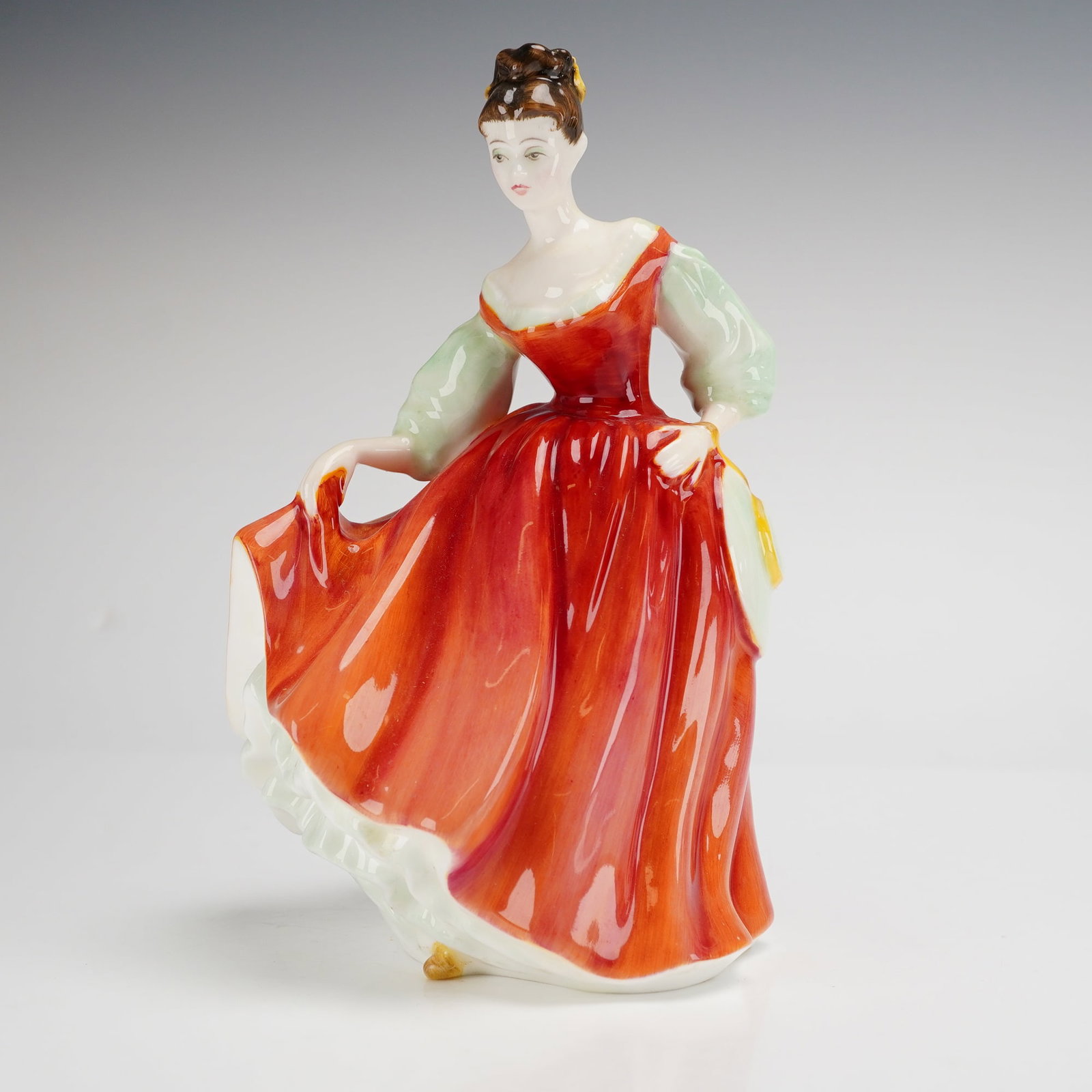 Royal Doulton Bone China Figurine, Fair Lady HN2832: A Royal Doulton bone china figurine titled Fair Lady Red, model number HN2832. The figure depicts a standing woman in a mid-20th-century interpretation of historical dress. The subject wears a hand-pa