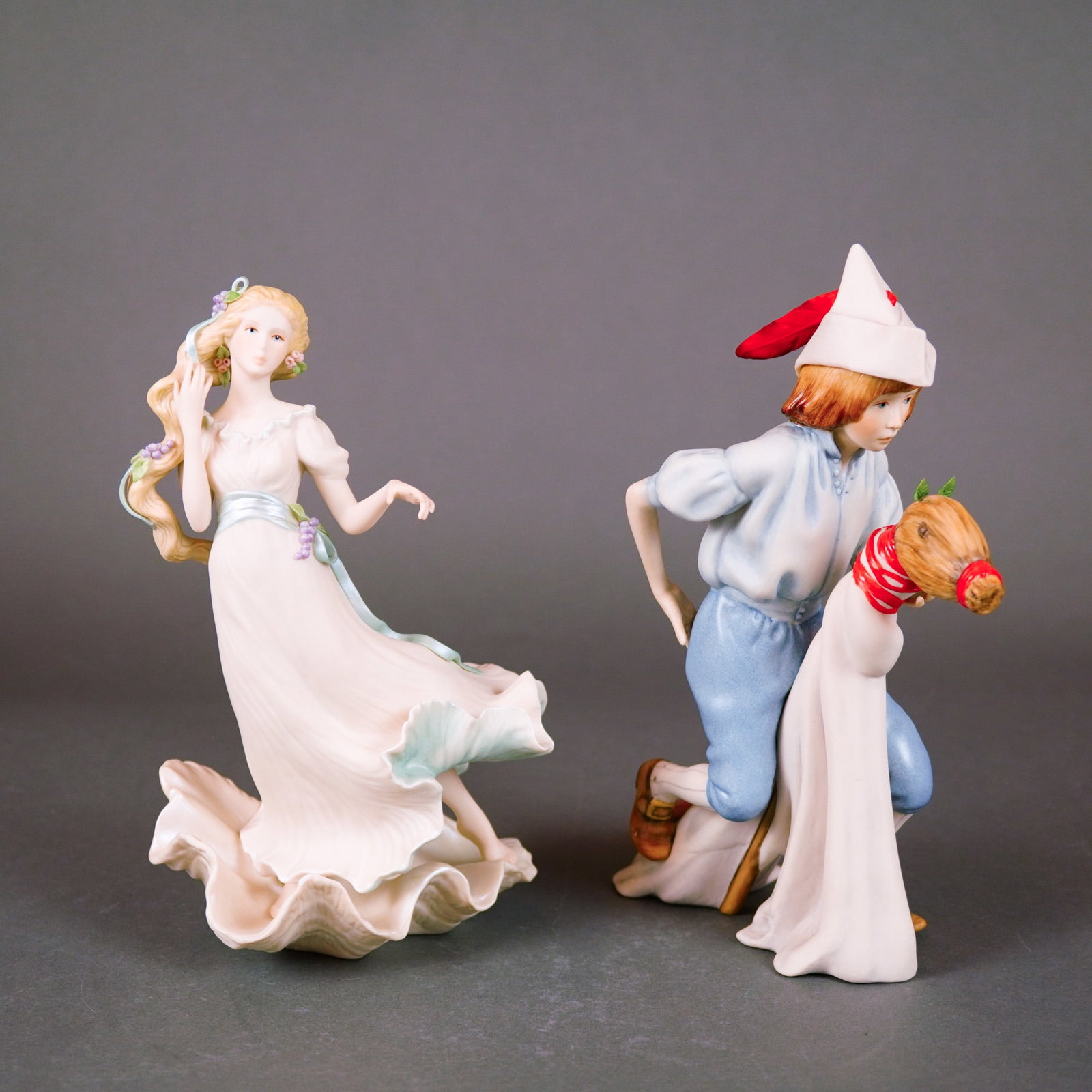 2pc Cybis Porcelain Figurine, Aphrodite and Yankee Doodle Dandy: The collection includes a figure of the goddess Aphrodite, standing within a stylized iridescent seashell, with blonde hair and a white gown accented in pale green. Also included is Yankee Doodle Dand