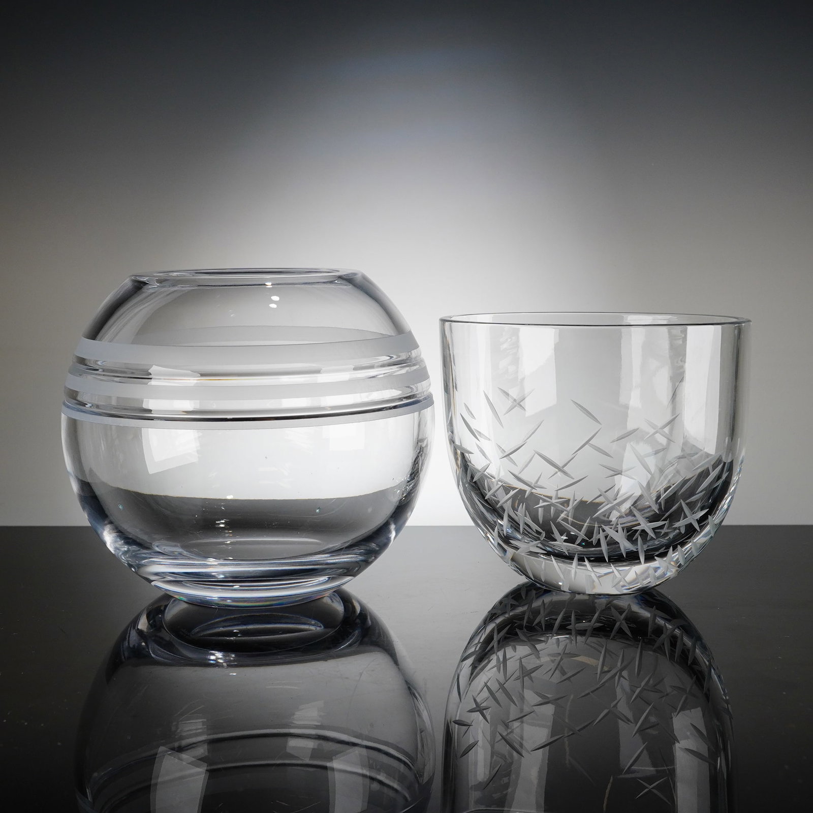2pc Kate Spade New York Crystal Rose Bowls: A duo of contemporary clear crystal rose bowls by Lenox for Kate Spade New York. It includes one Library Stripe rose bowl of spherical form, featuring three horizontal frosted bands encircling the cen