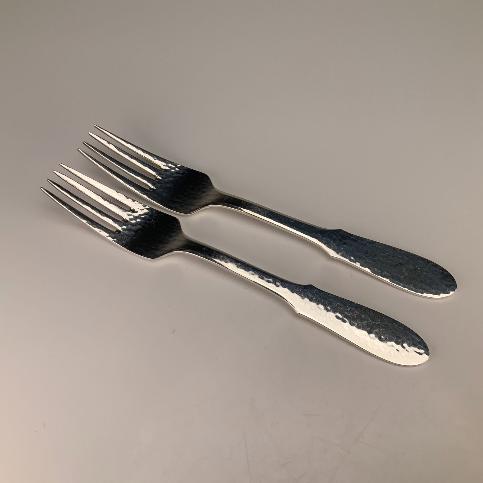 A Pair of Georg Jensen Mermaid Pattern EPNS Silverplate Dinner Forks: A pair of silver plated dinner forks in the Mermaid pattern by Georg Jensen. These pieces are manufactured in Denmark and constructed from electroplated nickel silver (EPNS). The design is defined by 