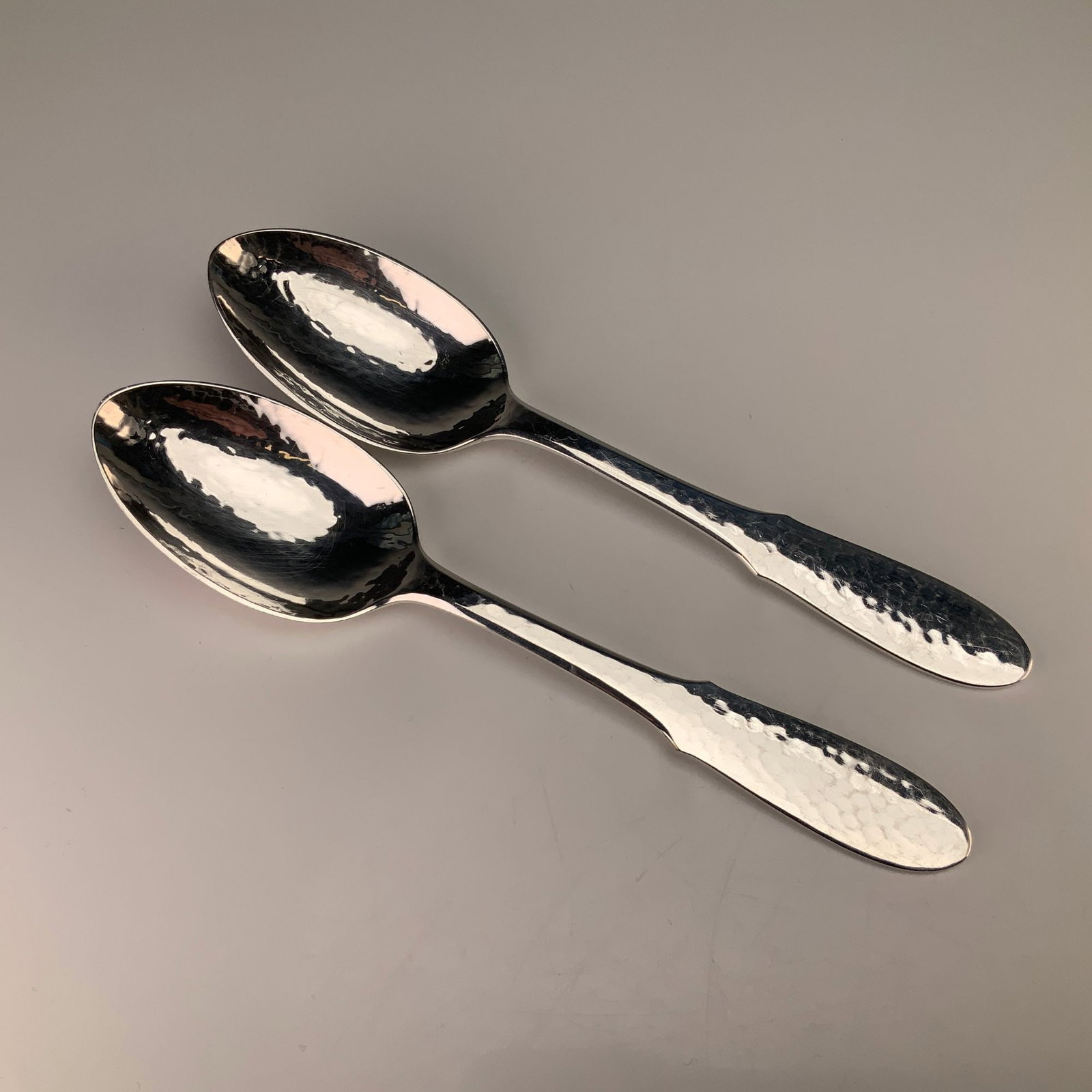 A Pair of Georg Jensen Mermaid Pattern Silver-Plated Place Soup Spoons: A pair of silver-plated place or oval soup spoons in the Mermaid pattern by Georg Jensen. These items are manufactured from electroplated nickel silver and feature a hand-hammered martele finish on bo