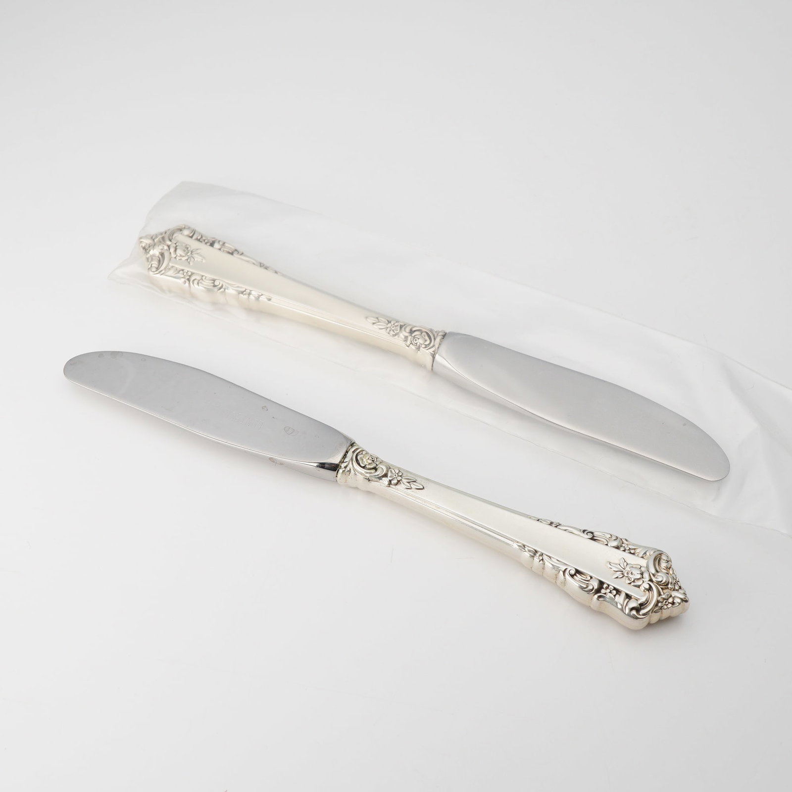 2pc Lunt Sterling Silver and Stainless Steel Butter Spreaders Knives, Rondelay: A pair of butter spreaders by Lunt Silversmiths in the ornate Rondelay pattern. This 2pc set features sterling silver handles with stainless steel blades. The handles display the characteristic pierce
