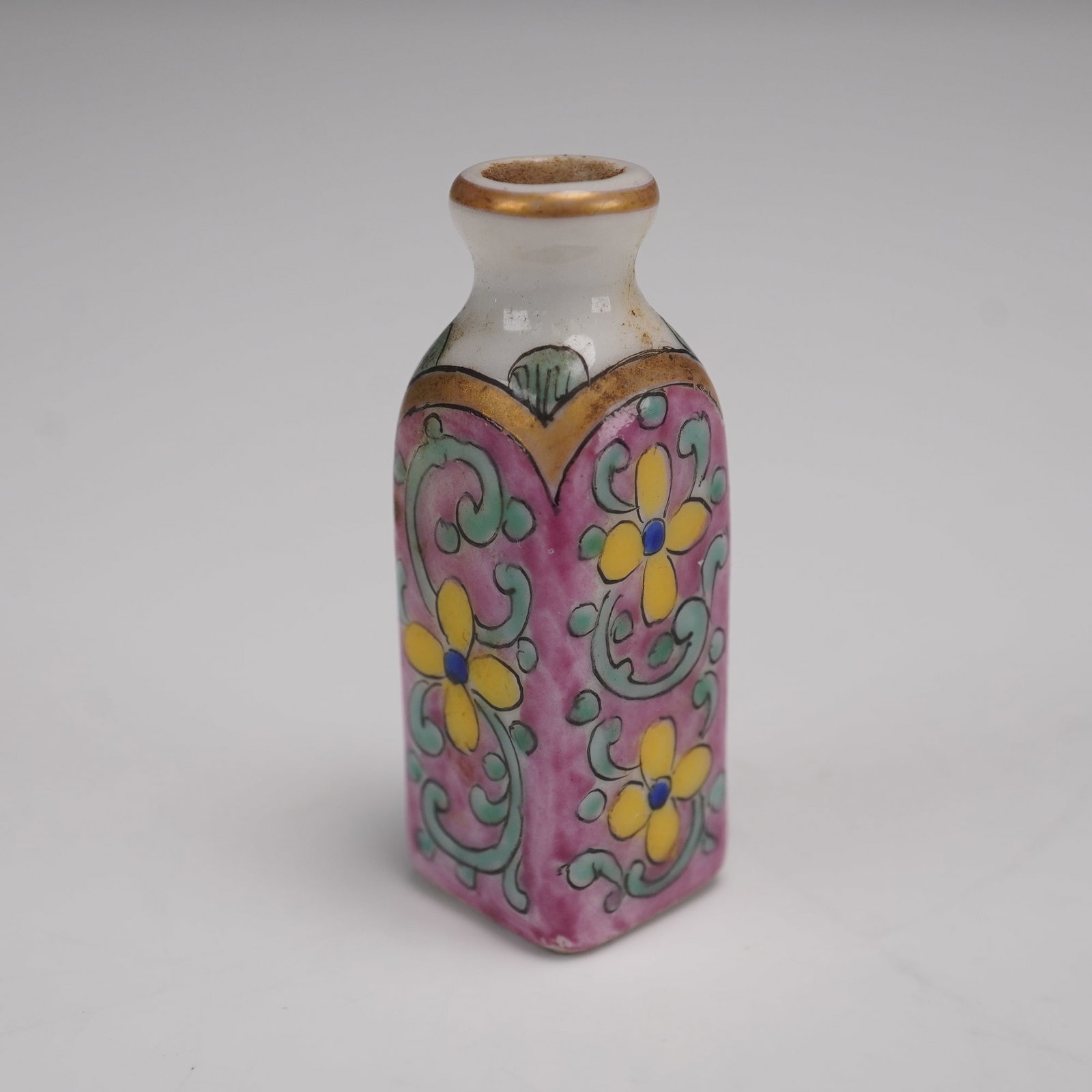 Porcelain Hand Decorated Snuff Bottle: A porcelain hand-decorated snuff bottle featuring a vibrant floral motif with yellow blossoms against a pink ground. The decoration is accented with green scrollwork and gold detailing around the neck