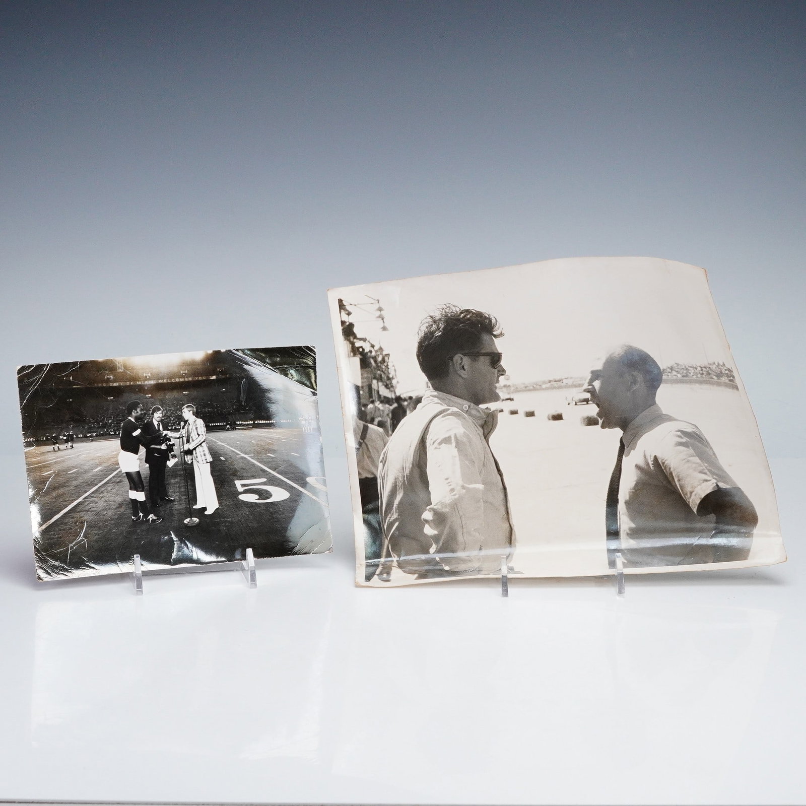 Pair of Vintage Press Photographs- Mario Andretti and Pele: A pair of vintage black and white press photographs depicting two iconic figures from the world of sports. The first shows legendary race car driver Mario Andretti, likely at the Indianapolis 500, in 