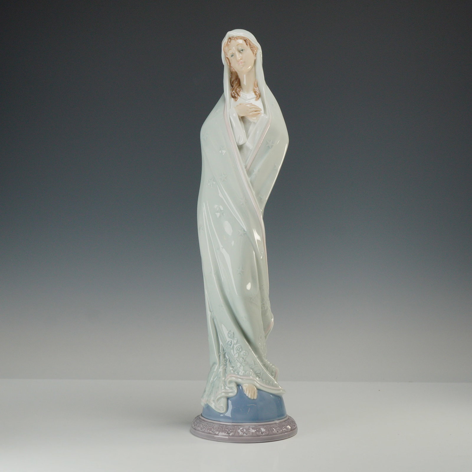 Lladro Porcelain Figurine 6631 Sweet Mary: This Lladro porcelain figurine, model number 6631, is titled Sweet Mary. The piece features a tall, slender representation of the Virgin Mary in a pensive pose with her hands crossed over her chest. S