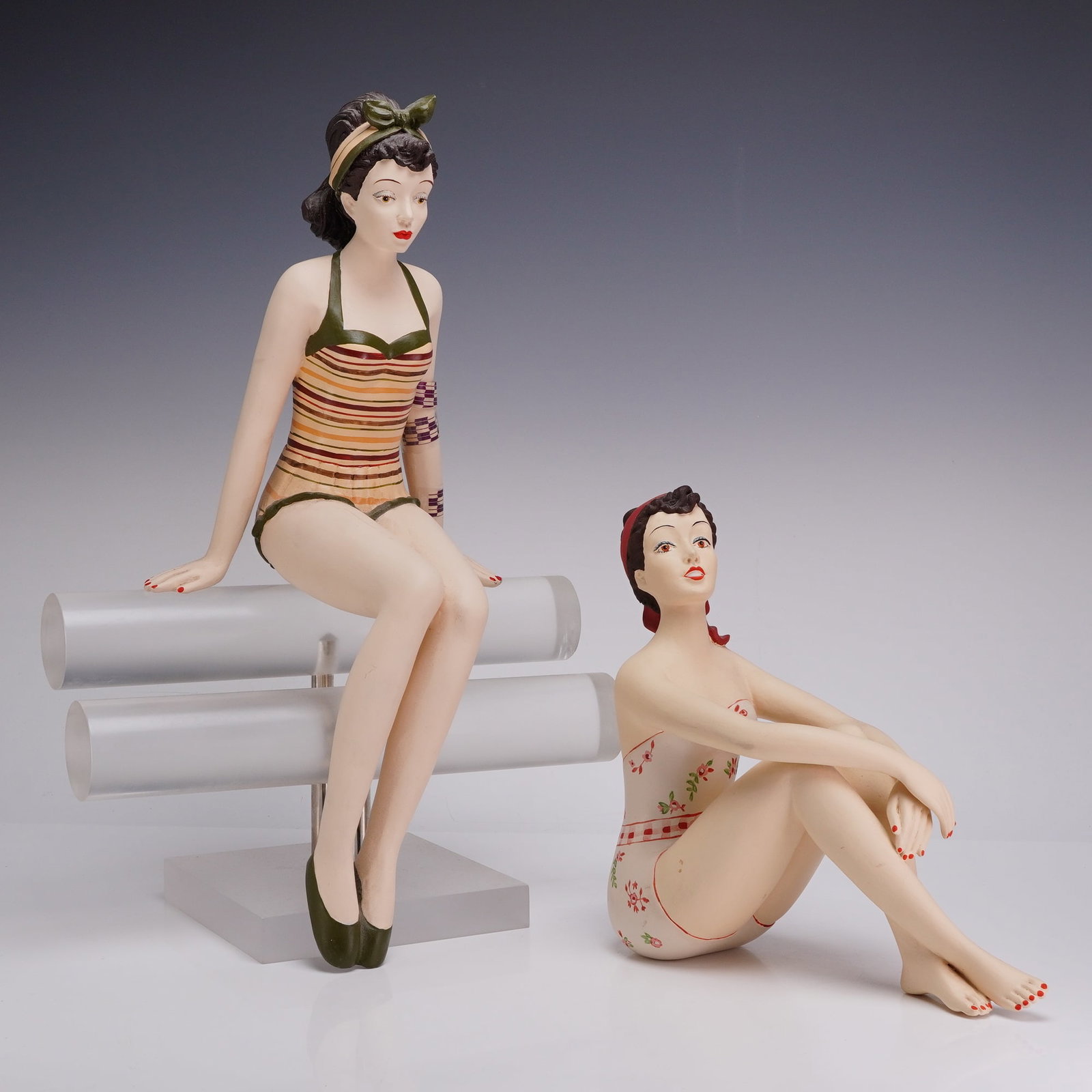 Two Retro Style Bathing Beauty Girls in Swim Suits Figurines: This lot consists of two contemporary decorative figurines of girls in swim suits, modeled in a mid-century seaside aesthetic. Both items are constructed from a painted matte-finish polyresin composit