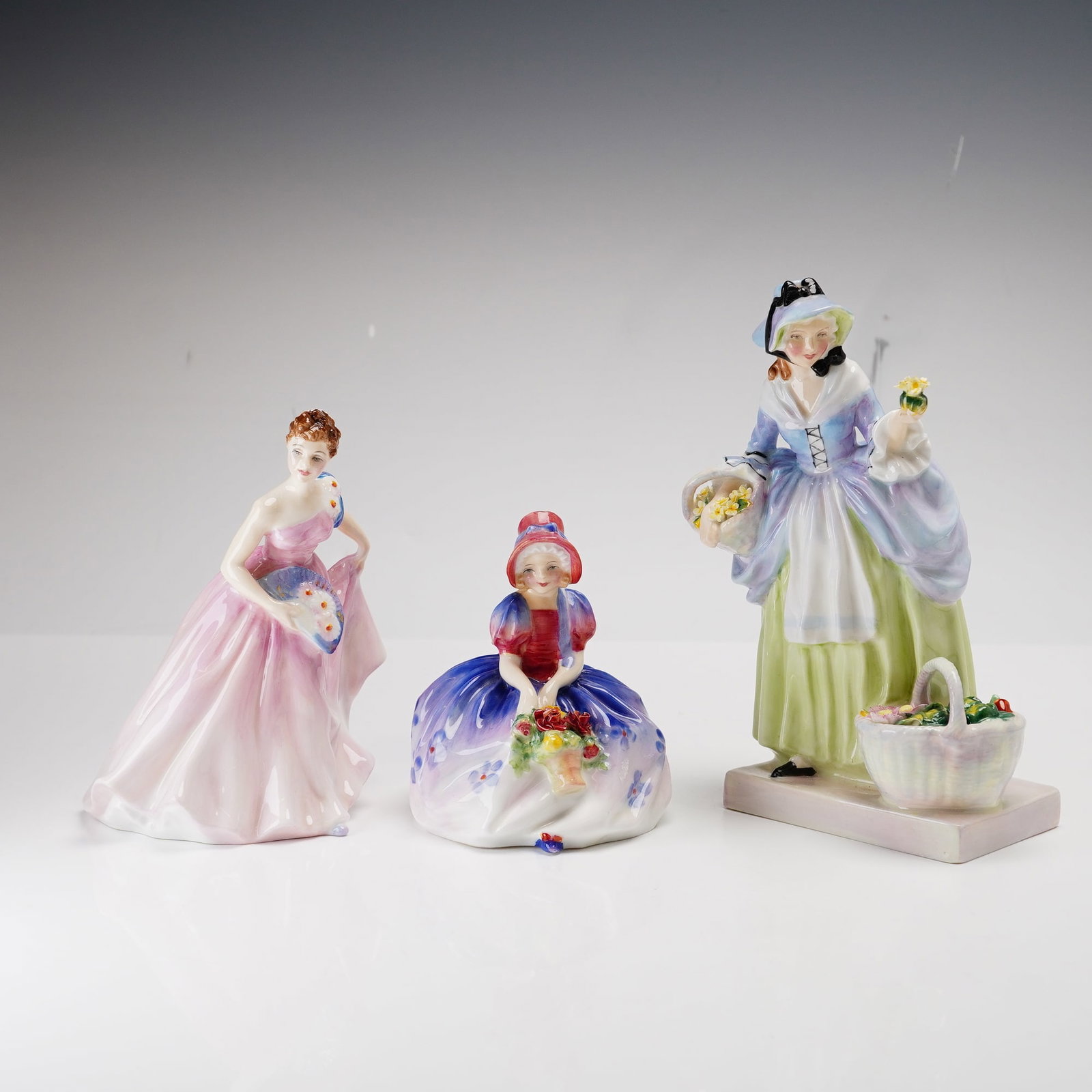 Three Royal Doulton Figurines- Invitation HN2170, Monica HN1467 and Springflowers HN1807: This lot consists of three Royal Doulton molded and hand-painted glazed bone china figurines, identified by the lot marking rdf x 3. The first figure is Invitation, model HN 2170, designed by Margaret