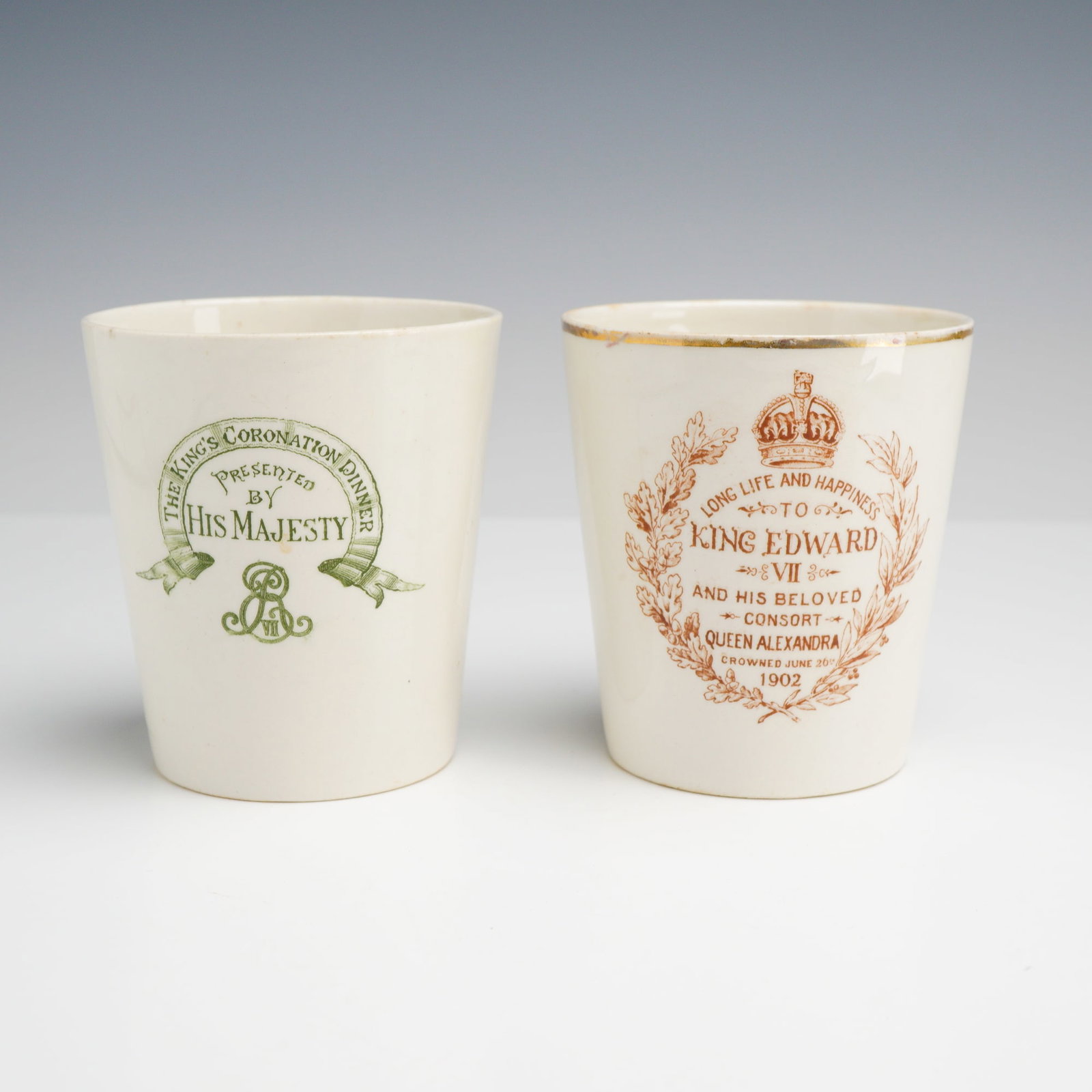 2pc Royal Doulton King Edward VII and Queen Alexandra 1902 Coronation Earthenware Beakers: This lot consists of two earthenware commemorative beakers manufactured by Royal Doulton for the 1902 coronation of King Edward VII and Queen Alexandra. The first beaker is decorated with green transf