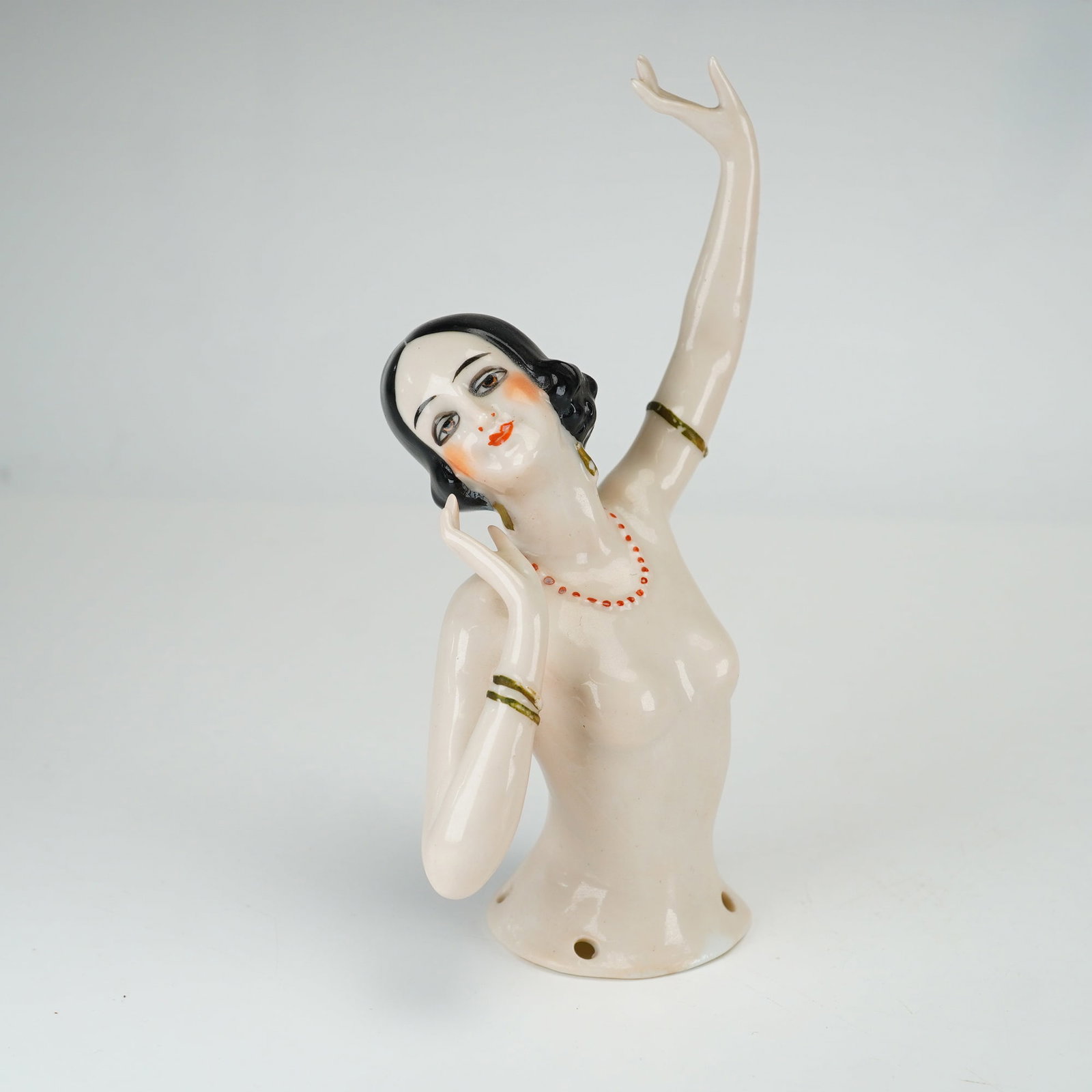 Art Deco Painted Porcelain Half Doll: This Art Deco style glazed porcelain half doll features a stylized female figure in an expressive theatrical pose with her left arm raised and her right hand positioned near her cheek. The figure is m