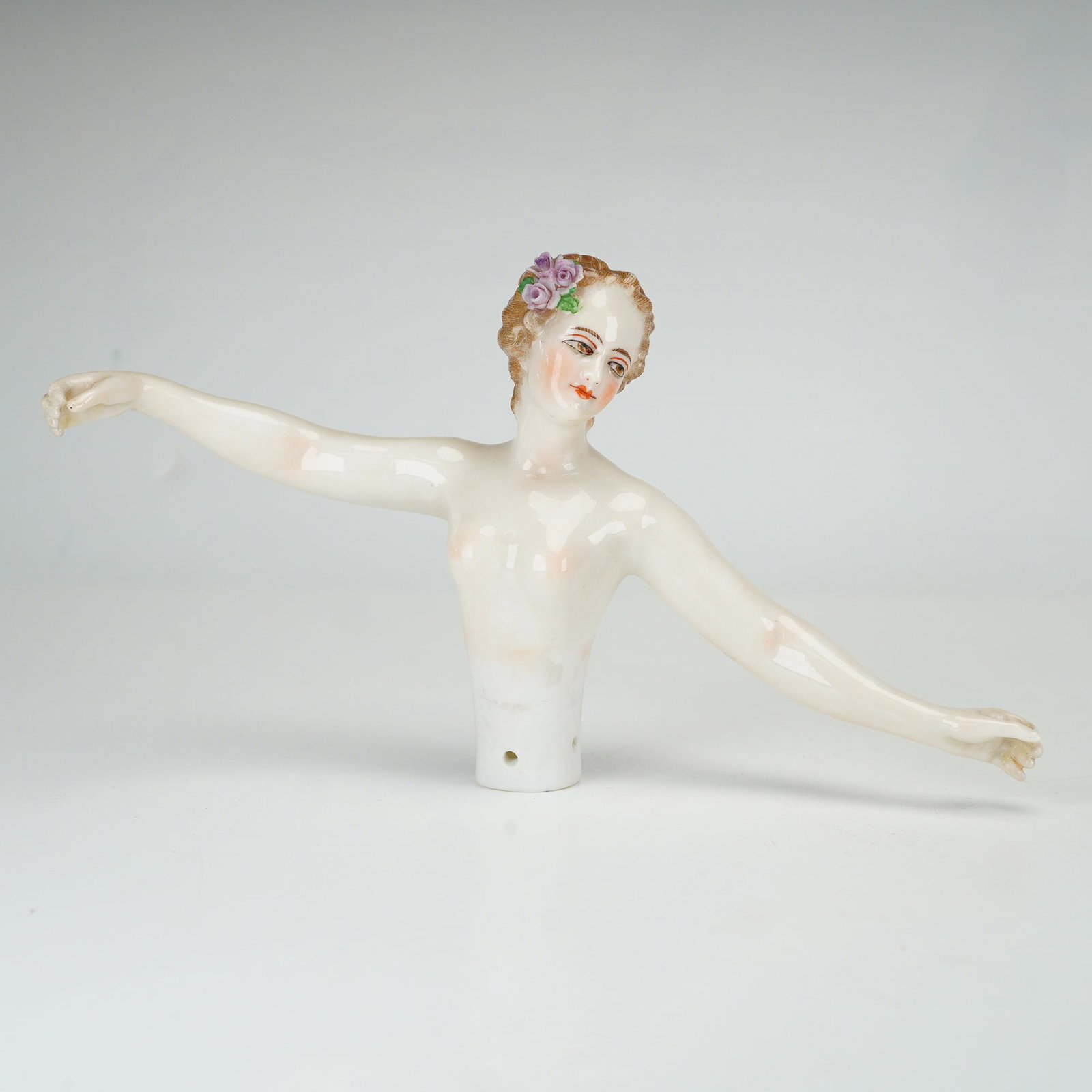 German Porcelain Half Doll with Outstretched Arms: This porcelain half doll depicts a nude female torso with arms outstretched in a graceful pose. The figure is crafted from glazed porcelain with hand-painted facial features, including brown eyes, fin