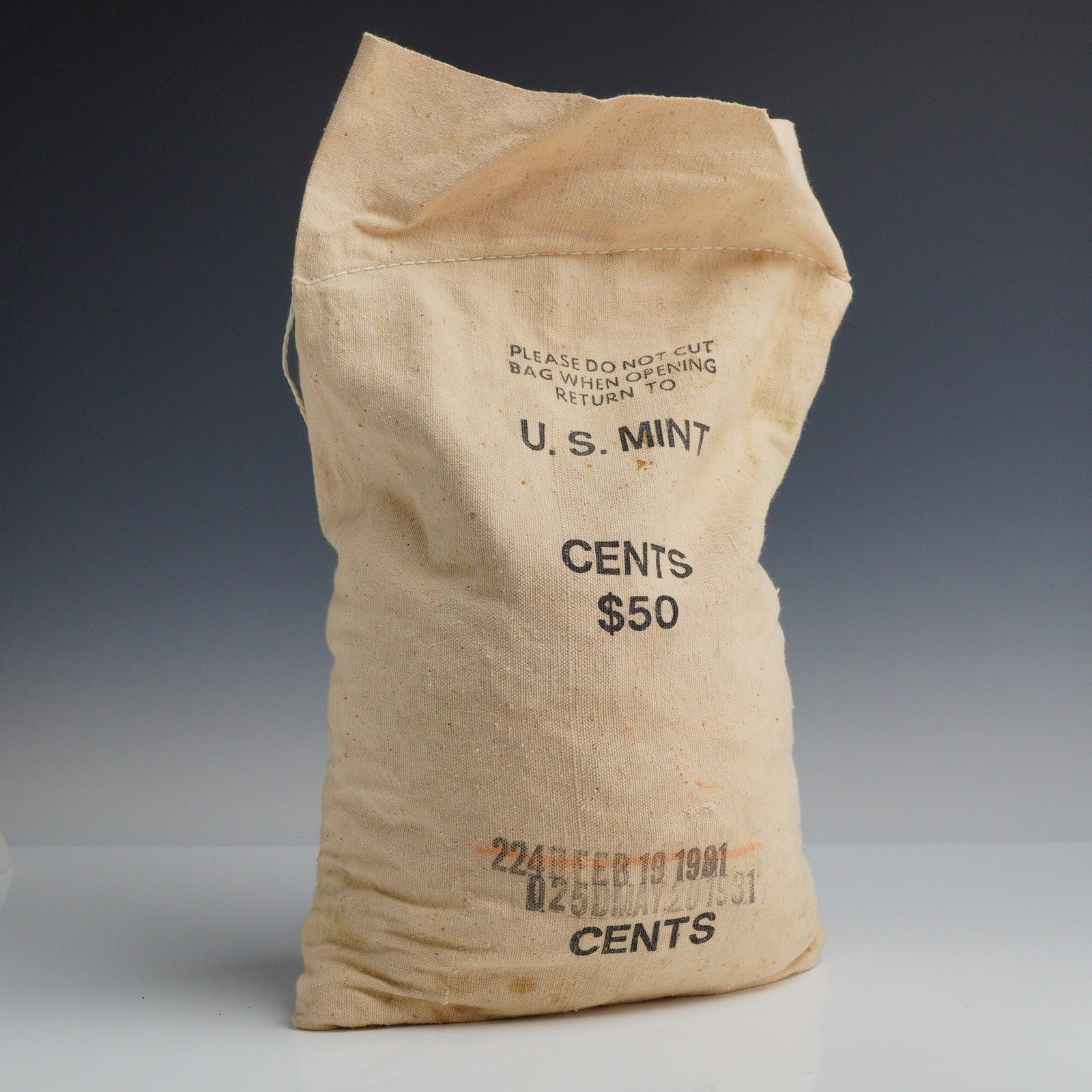1981 US Mint 50.00 Dollar Bag of Pennies: This original US mint $50.00 bag of pennies contains 5,000 cents. The item is a heavy cream-colored canvas bag tied shut at the neck with a white cord. The exterior features printed black text: PLEASE