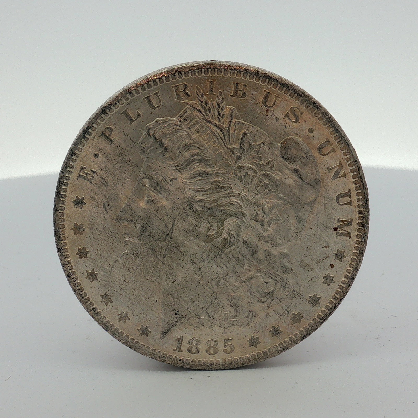 1885-O US Morgan Silver Dollar: This US Morgan dollar is a silver coin struck at the New Orleans Mint. The coin features the Liberty Head obverse and the Eagle with Wreath reverse. An O mint mark is located on the reverse, centered 