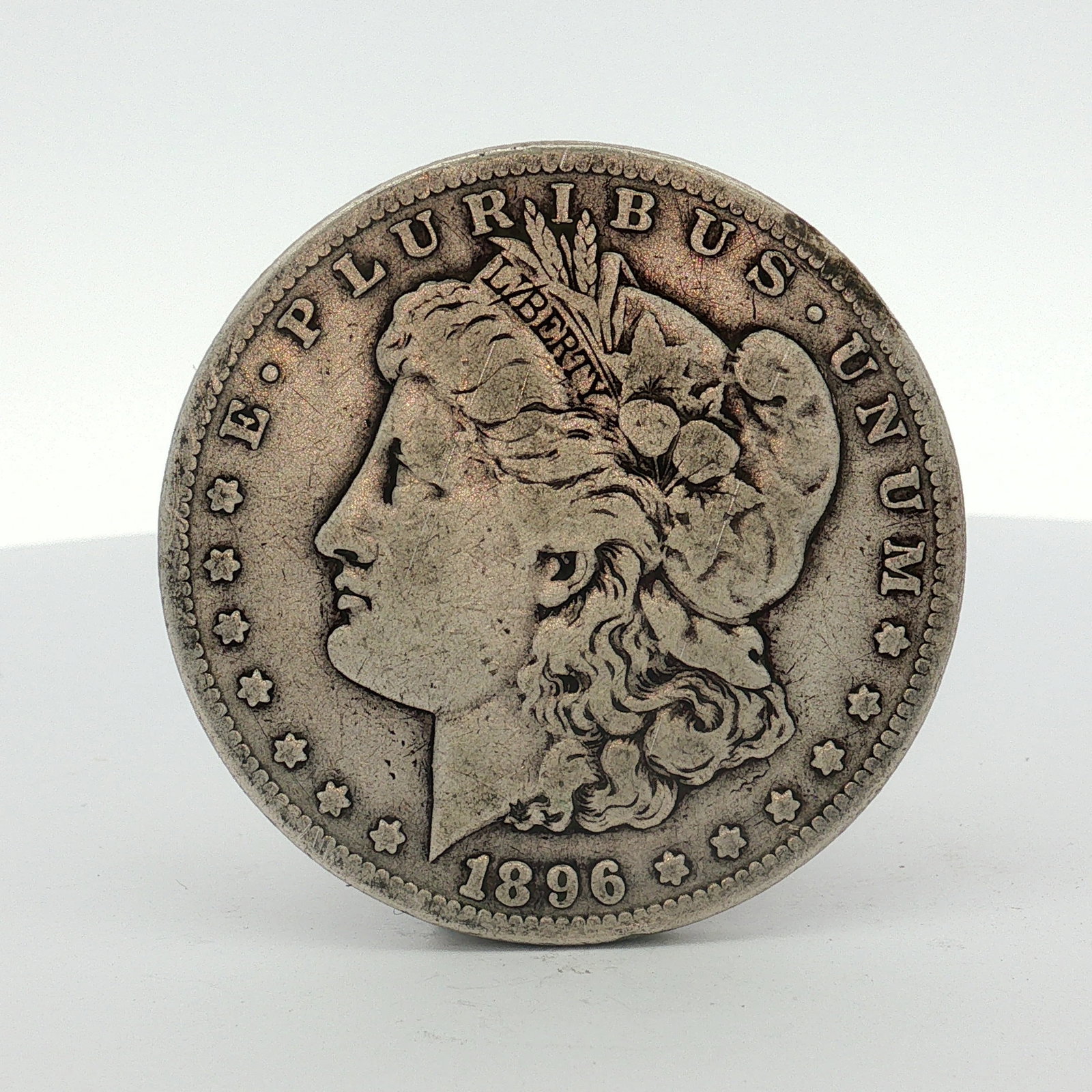1896-S US One Dollar Morgan Silver Dollar, Circulated: This 1896-S US Morgan silver dollar was struck at the San Francisco Mint. The coin is composed of 90% silver and 10% copper. The obverse features the George T. Morgan Liberty head design, bordered by 