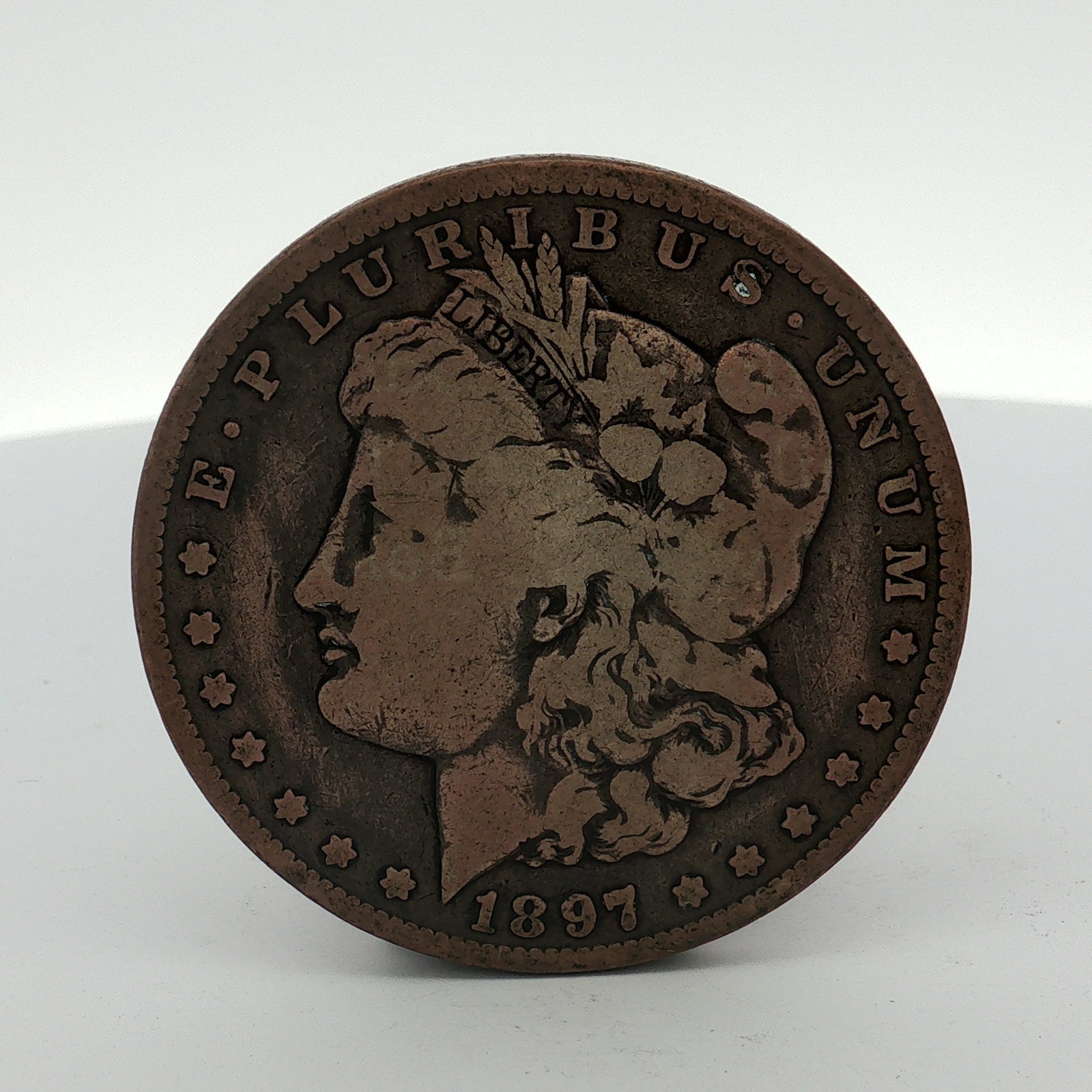 1897-O US Morgan Silver Dollar Coin Circulated: This US Morgan 1897-O was minted in New Orleans. The piece is struck in a copper-toned metal, which is atypical for the standard 90 percent silver composition of official US currency. The O mint mark 