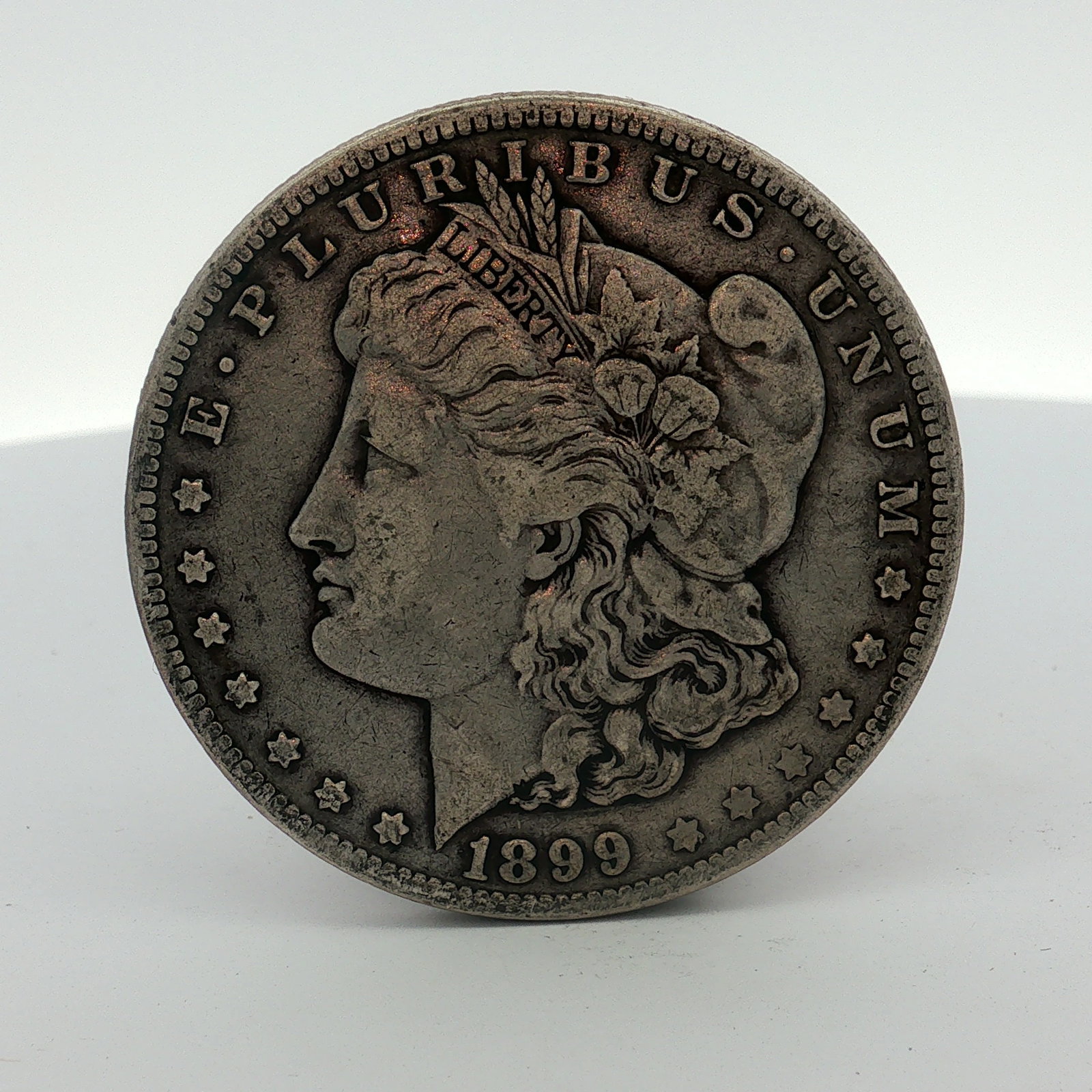 1899-O US Morgan Silver Dollar Coin Circulated: This coin was struck at the New Orleans Mint and is composed of 90 percent silver and 10 percent copper. The piece features the Liberty Head obverse and the heraldic eagle reverse. Obverse inscription