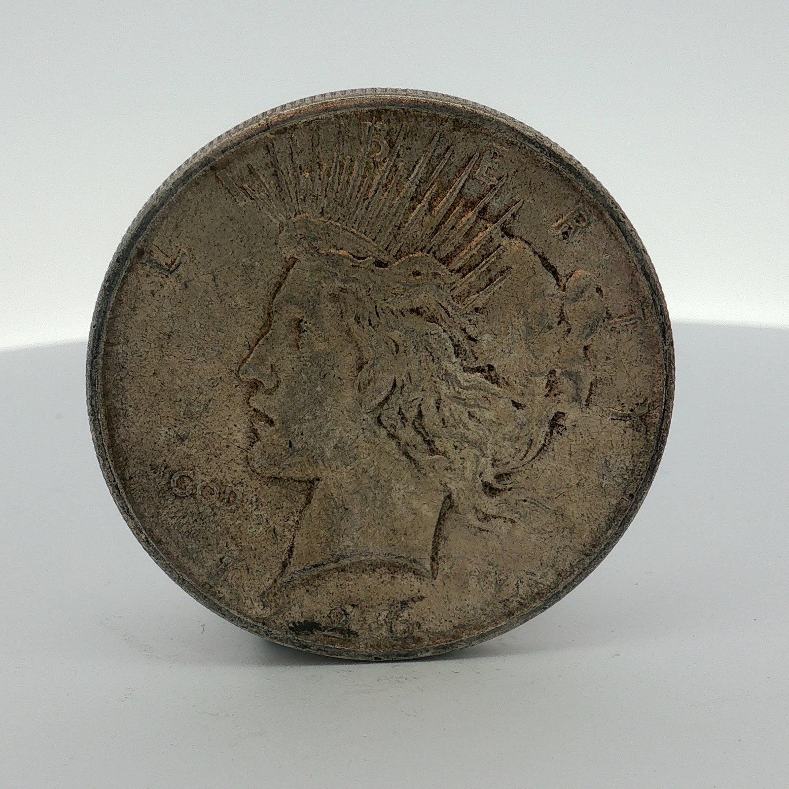 1926-D US One Dollar Peace Silver Dollar, Circulated: This 1926-D US Peace silver dollar was struck at the Denver Mint. The coin is composed of silver and features a reeded edge. The obverse displays the Peace dollar type with the date 1926 and the inscr
