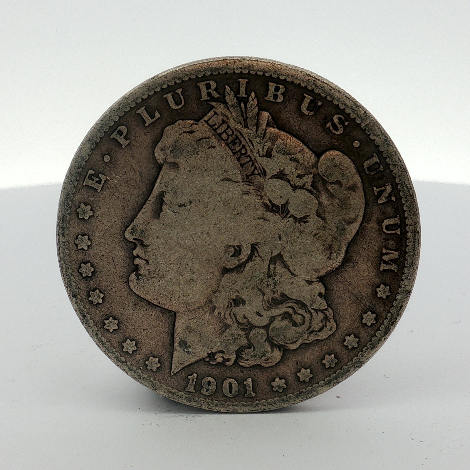US 1901-O Morgan Silver Dollar: This coin is composed of .900 silver and .100 copper. The obverse features the Liberty head design with the date 1901 and the legend E PLURIBUS UNUM. The reverse displays the heraldic eagle design, th
