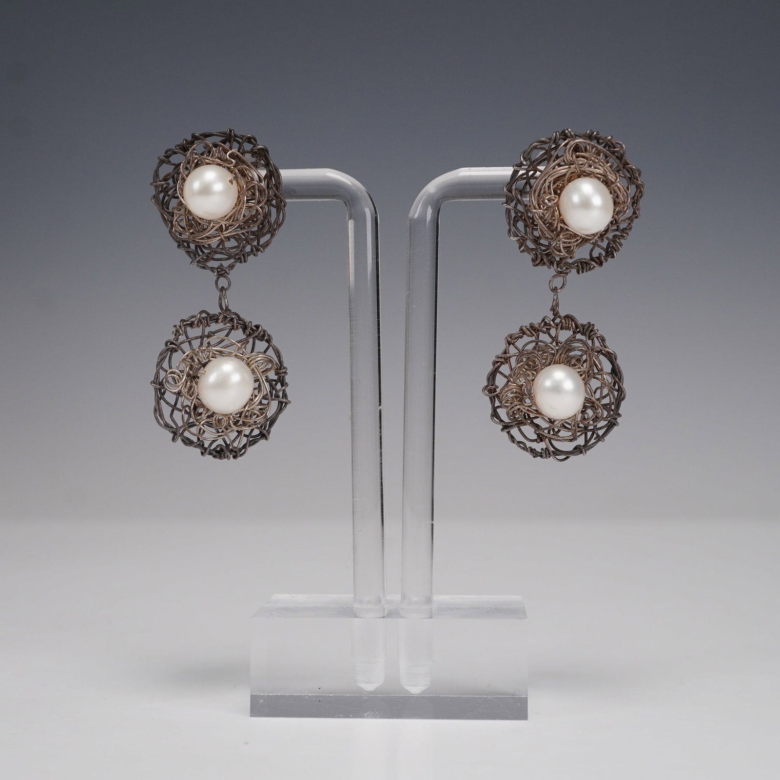2pc Wirework Drop Earrings with Simulated Pearls: Pair of striking drop earrings featuring sculptural wirework orbs in dark metal tones, each encasing a large simulated pearl at center. Double-orb design with articulated drops, giving them dramatic m