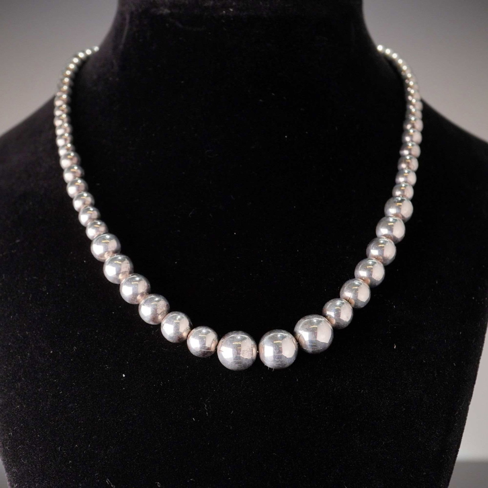 Tiffany & Co. Hardwear Graduated Sterling Silver Ball Necklace: This Tiffany & Co. Hardwear collection graduated sterling silver ball necklace features polished spherical beads that increase in diameter toward the center. The necklace includes a small circular
