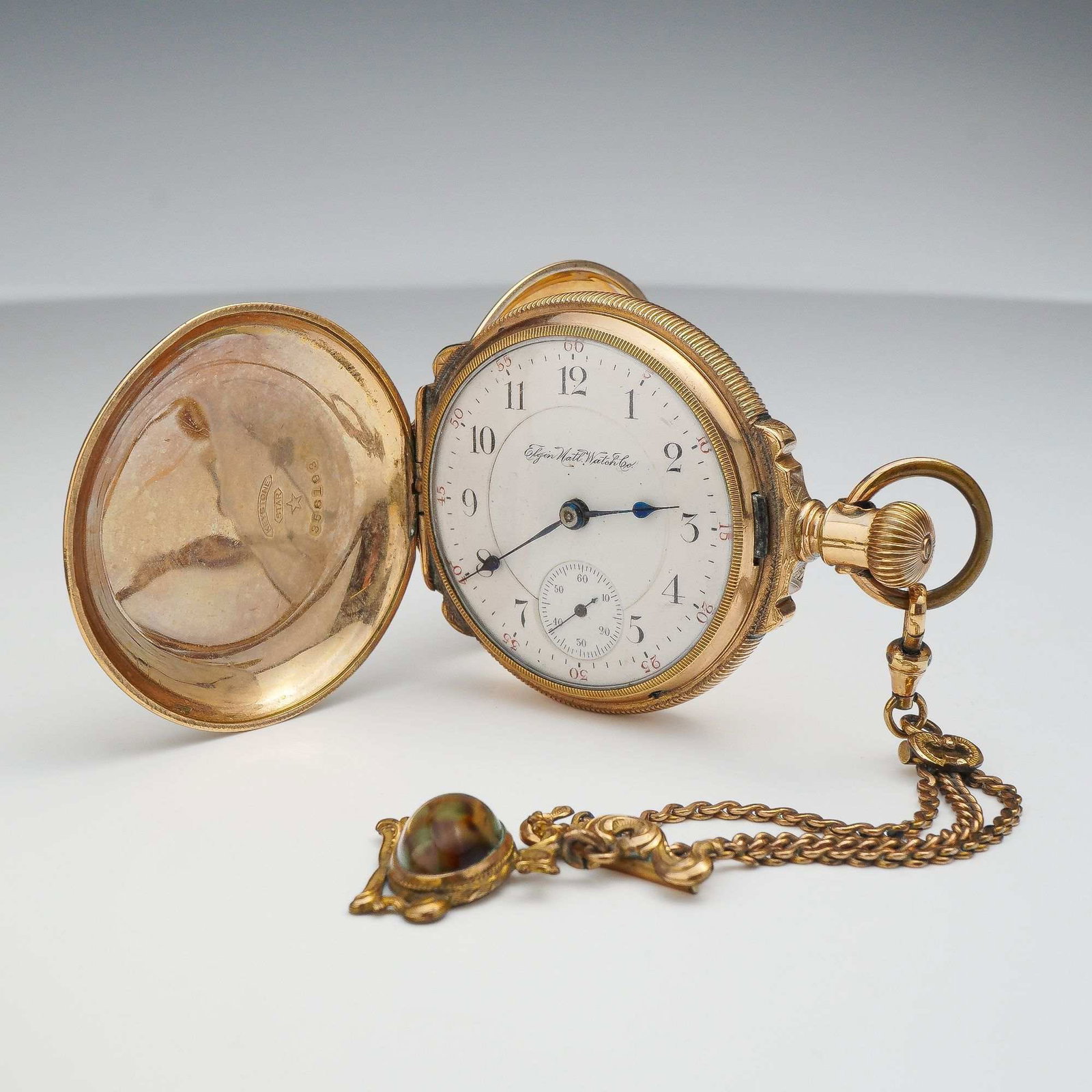 Elgin National Watch Co. 10K Gold Hunting Case Pocket Watch and Fob Chain: Elgin National Watch Co. hunting-case pocket watch. Manual wind mechanical movement featuring 15 jewels, marked Adjusted with serial number 6360973. The white enamel dial displays black Arabic