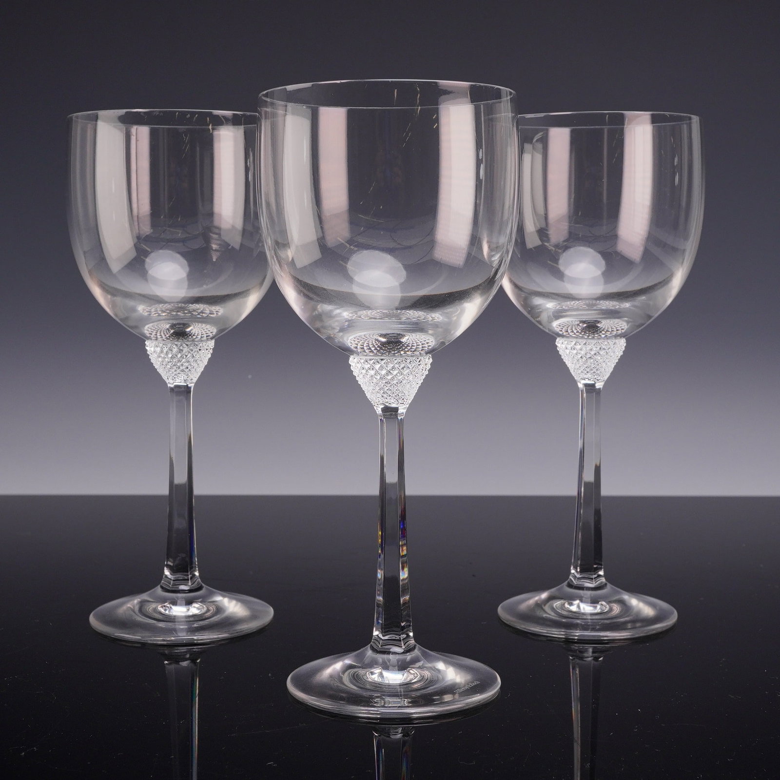 Three Villeroy & Boch Crystal Water Goblets in the Octavie Pattern: A trio of Villeroy & Boch crystal water goblets in the Octavie pattern. Each glass features a large, rounded balloon-style bowl. The bowl sits atop a decorative frosted knop with a diamond-cut texture