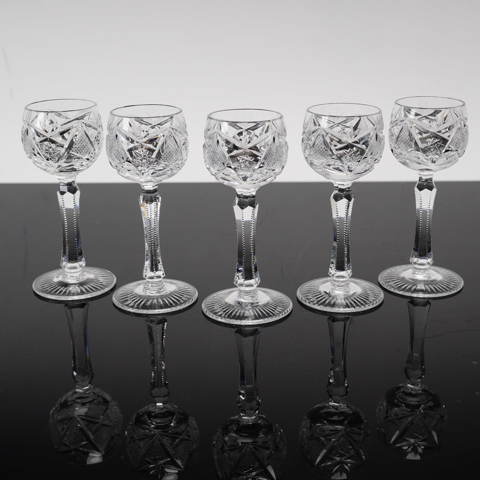 Set of Five Imperial Crystal Cordial Glasses, Avondale: The design features a round bowl decorated with deeply cut hobstars alternating with diamond cross-hatching and fan motifs. The glasses are supported by hexagonal faceted stems with notched zipper cut