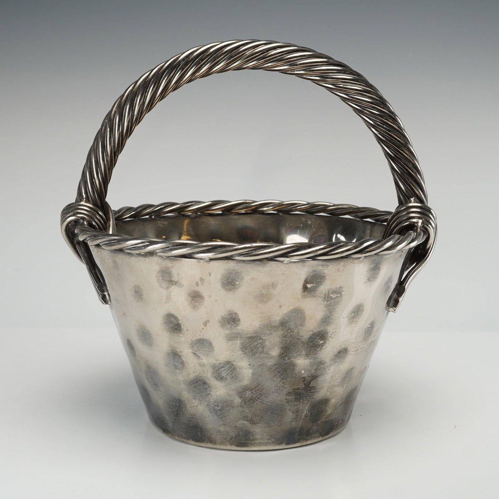 Vintage Spanish Silver-Plated Hammered Champagne Cooler Attributed to Valenti: This large hammered silver-plated champagne cooler is designed as a decorative basket with a fixed arching handle. The tapered circular body features a pronounced dimpled finish throughout the exterio