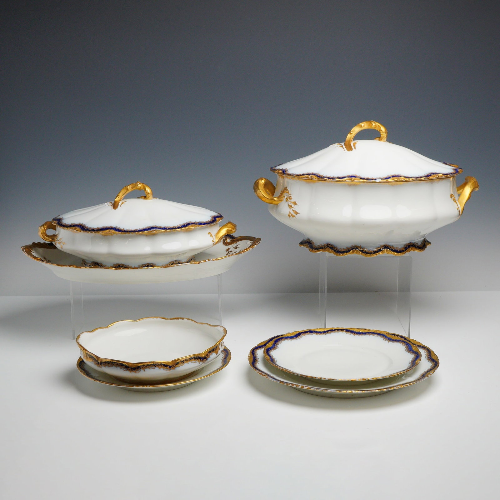 7pc Theodore Haviland Limoges Cobalt and Gilt Porcelain Tableware: This group of porcelain bears the authentic factory mark of Theodore Haviland, Limoges, France. The pieces are constructed from fine white porcelain featuring a scalloped and lobed form. The