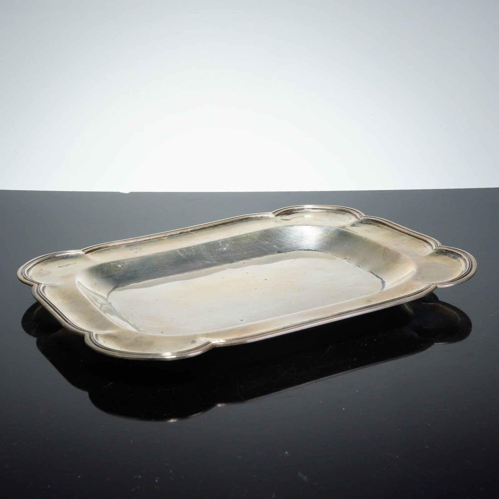Argenta Sterling Silver Rectangular Vanity Tray: The tray features a lobed or scalloped rim with a raised, molded border and a shallow well with rounded corners. A hallmark is stamped within a rectangular cartouche along the upper edge of the revers