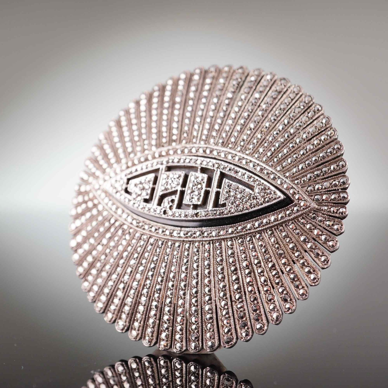 Large Art Deco Sterling Silver and Marcasite Vintage Initial Brooch: A large vintage Art Deco style circular brooch featuring a sunburst design with radiating textured rays. The piece is constructed from sterling silver and is pave-set throughout with numerous faceted 