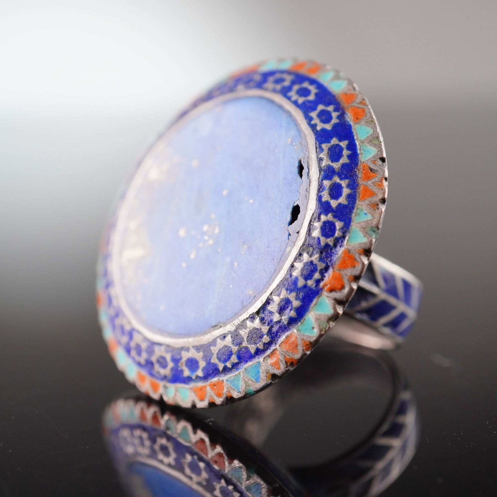 Large Pakistan Lapis Lazuli Statement Ring in the Style of Multan: This is a large, circular statement ring featuring a central lapis lazuli cabochon, in the craft traditions of Multan, Pakistan. The ring is constructed from a silver-toned white metal. The central fl