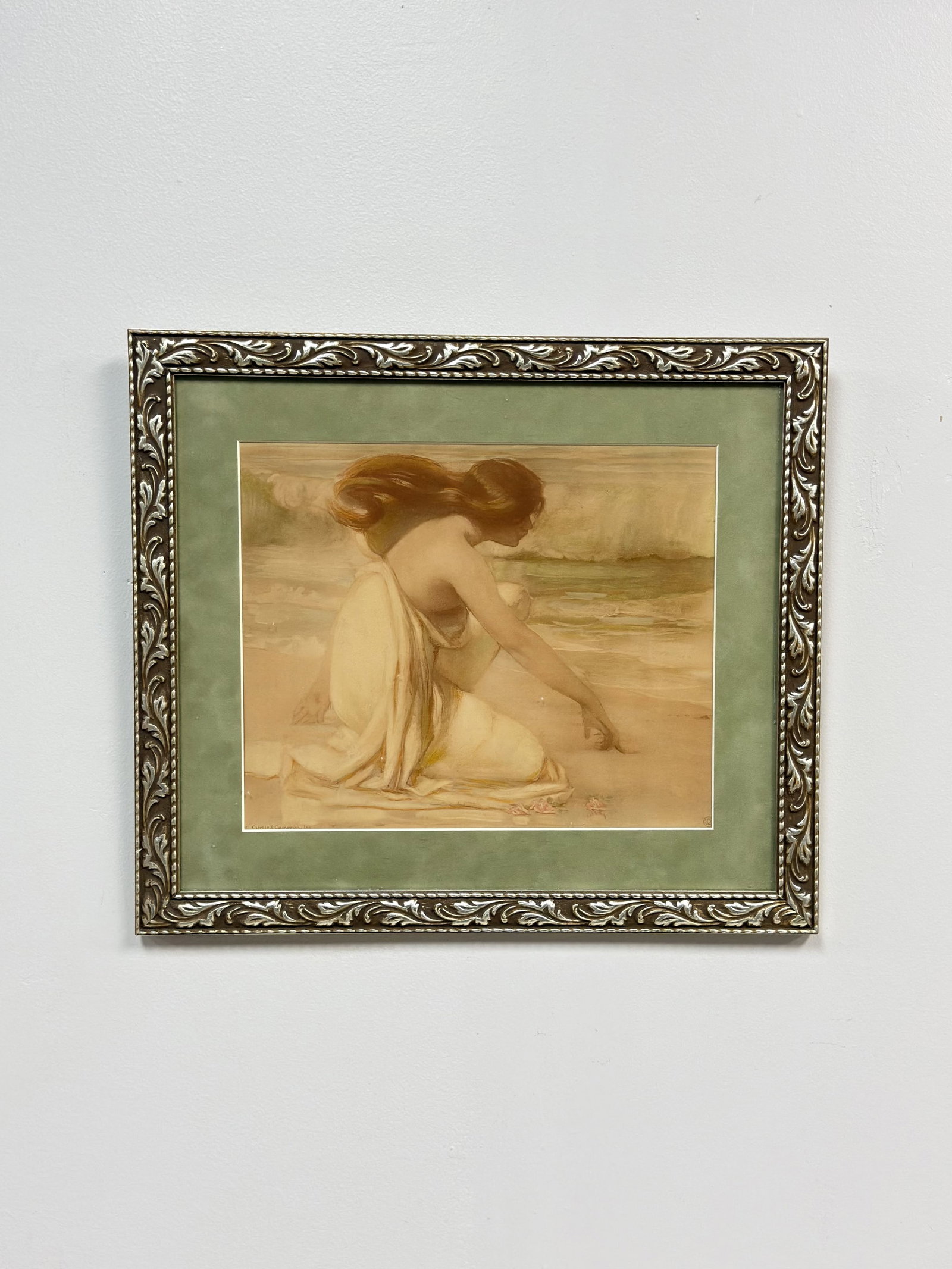 Curtis and Cameron Framed Copley Print of Woman Writing in the Sand: Published by Curtis and Cameron. The photomechanical color print depicts a woman with long auburn hair kneeling on a shoreline, rendered in a late Romantic aesthetic. The artwork features the printed 