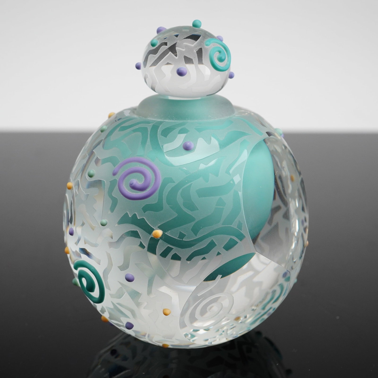 Susan Dimarchi Art Glass Perfume Bottle with Stopper: This studio art glass perfume bottle is the work of American artist Susan DiMarchi. The vessel features a spherical form constructed of heavy clear glass cased over an opaque matte teal core. The exte