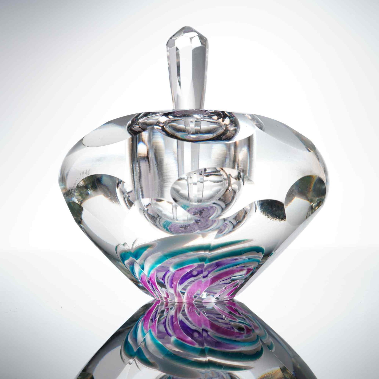 Chip Jones Art Glass Perfume Bottle and Stopper: This hand-blown art glass perfume bottle and stopper, by Chip Jones Art Glass, is dated 1996. The vessel is crafted from thick-walled clear glass in a squat, rounded form featuring an internal pink an