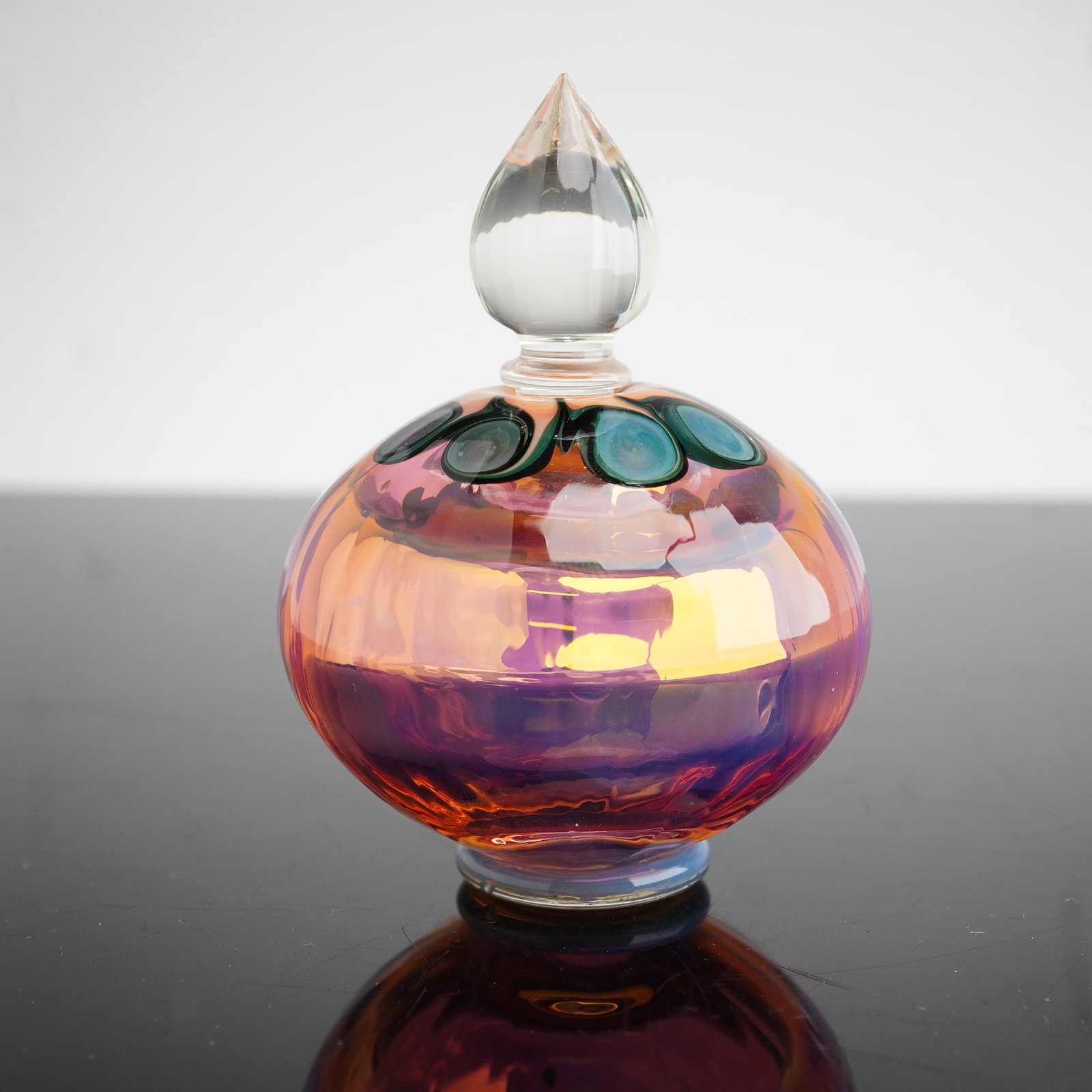 Richard Clements Iridescent Art Glass Scent Bottle and Stopper: The vessel features a squat, bulbous form decorated with a pulled eye or peacock feather motif around the shoulder. This decoration consists of teal and deep green concentric circles against a golden-