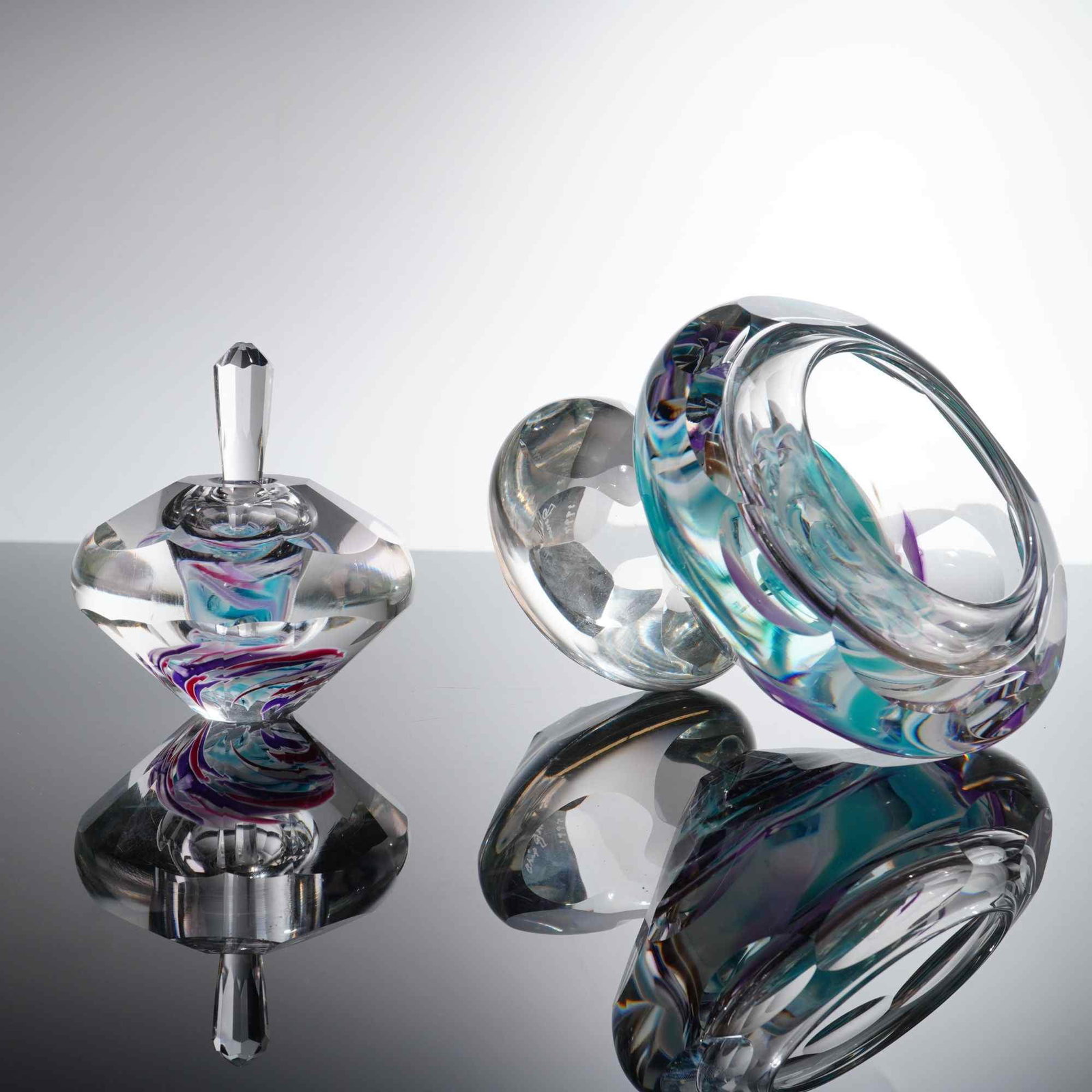 2pc Chip Jones Studio Art Glass Perfume Bottle and Figurine: This set of two studio art glass works by Chip Jones comprises a perfume bottle and an abstract sculpture figure. Both pieces are hand-blown in heavy, clear glass with internal decorative elements of 