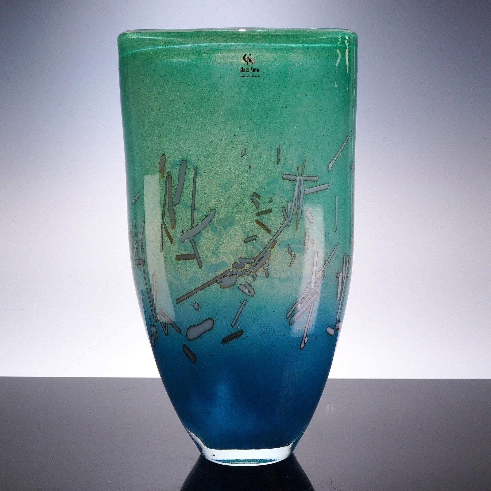 Glass Nuvo by Ian Hankey Blue and Green Art Glass Vase: The vase features a tall, tapered form with an elliptical cross-section. The glass is worked with a saturated color gradient, transitioning from a teal green at the rim to a deep cobalt blue at the ba