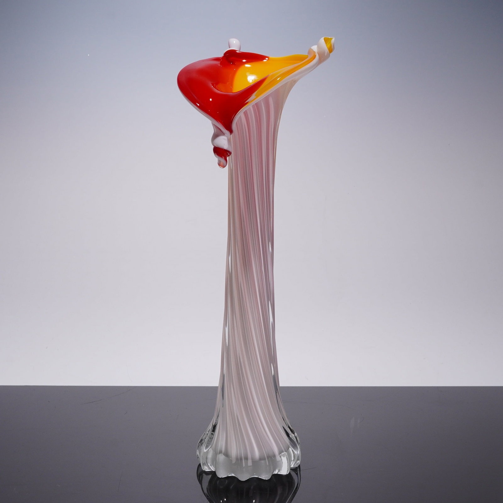 Jack-in-the-Pulpit Tall Hand-Blown Art Glass Vase: The vessel is composed of clear glass featuring internal, vertically aligned white and pale pink filigrana canes. The form features a slender body that rises to a dramatically flared and asymmetrical 