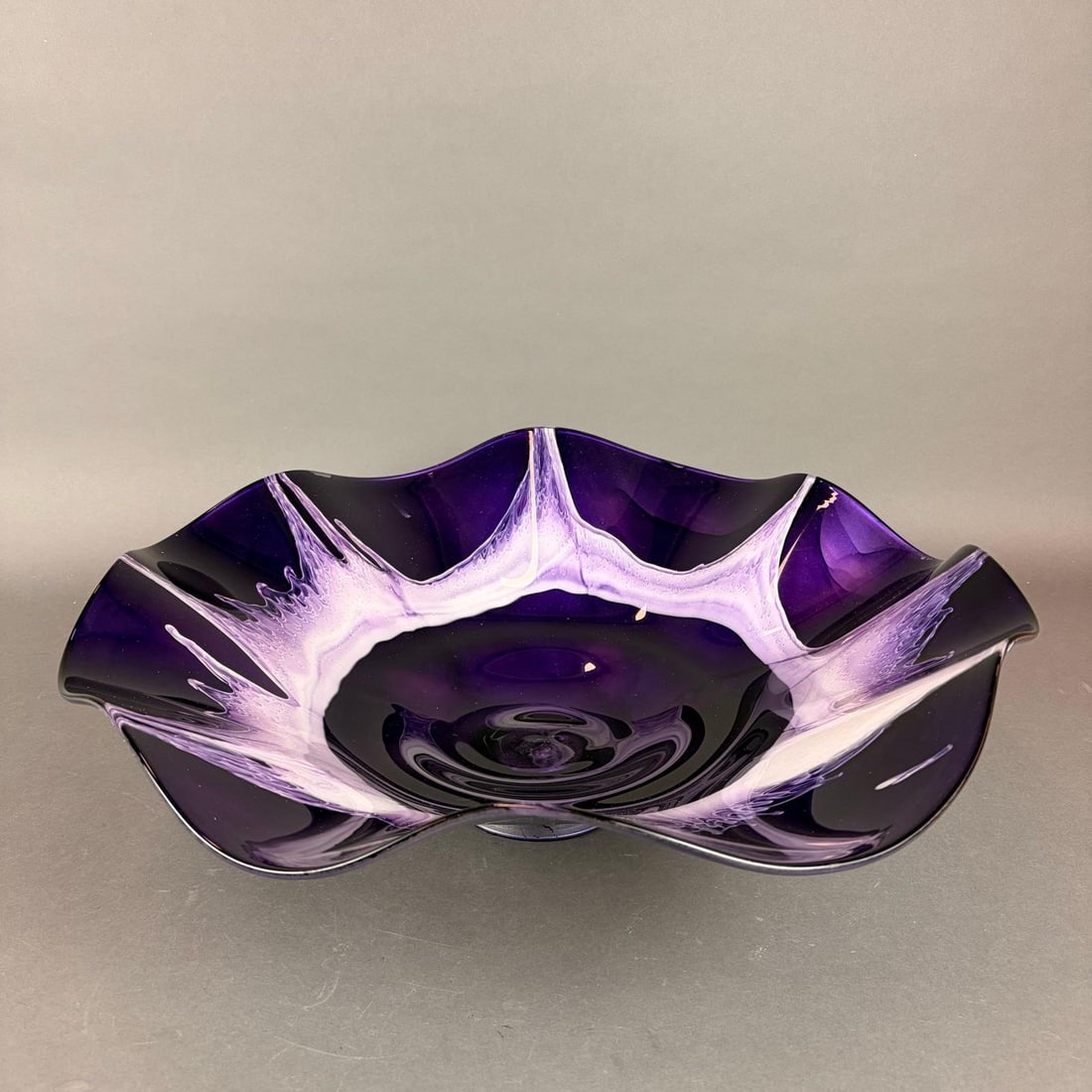 Hand-Blown Purple Art Glass Ruffled Centerpiece Bowl: This impressive art glass centerpiece bowl is a hand-made vessel crafted from purple glass with white internal decoration. The interior features a feathered band of opaque white and pale lavender radi
