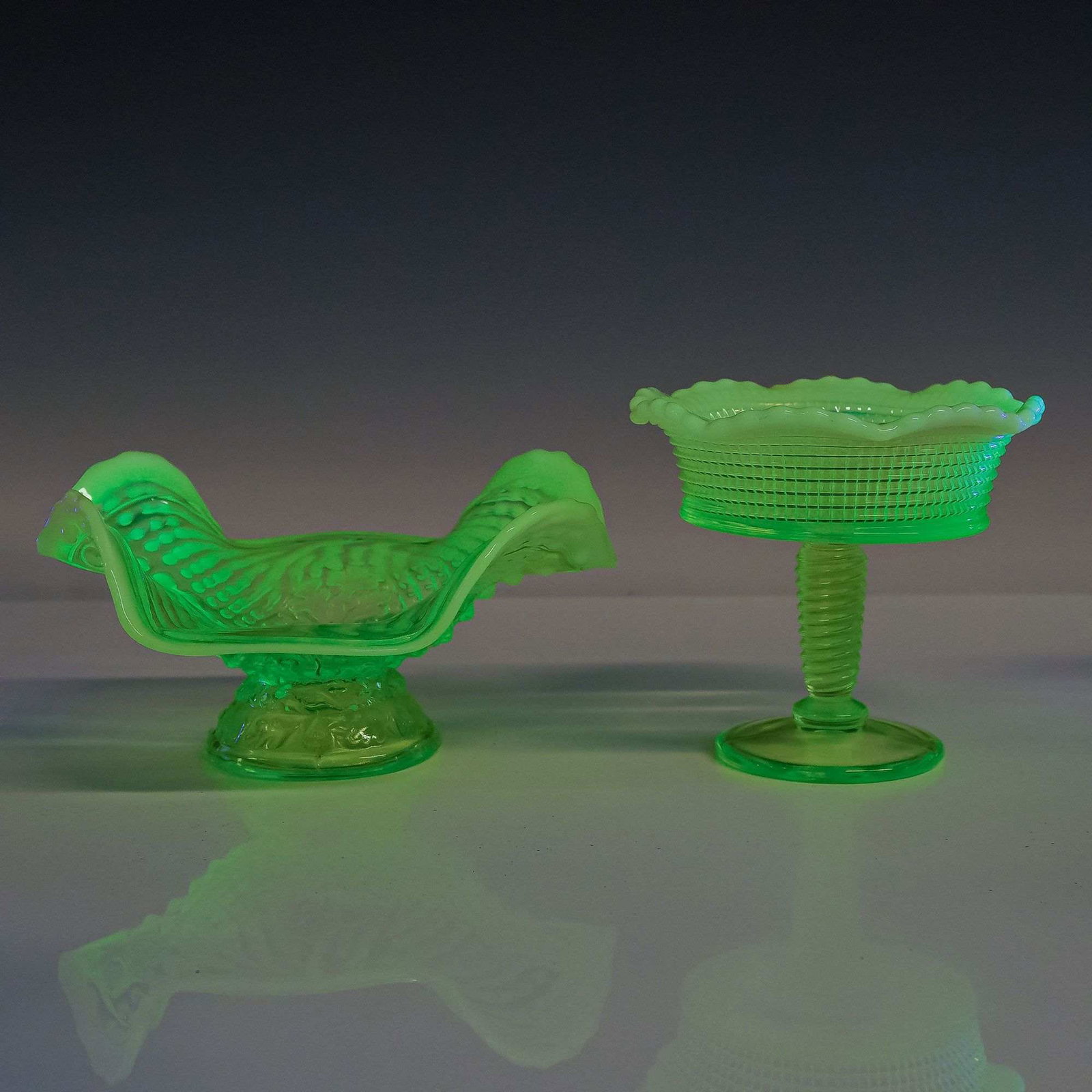 2pc American Uranium Glass Console Bowls: This lot consists of two pieces of American decorative pressed glass, both identified as yellow opalescent glass with uranium content. The first item is a footed bowl featuring vertical flowing folds 