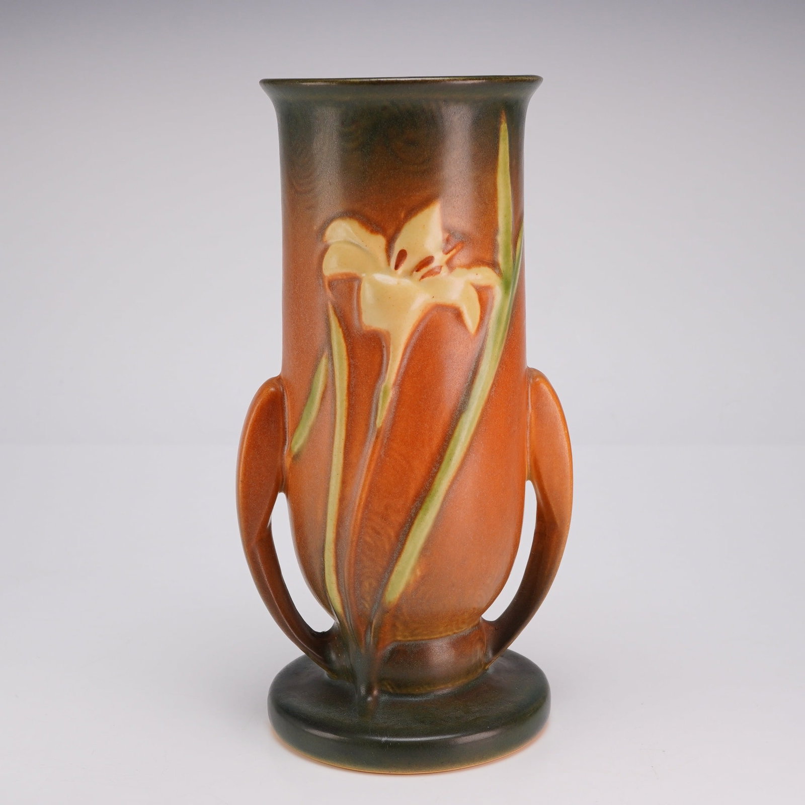 Roseville Pottery Dual Handled Vase, Brown Zephyr Lily: This Roseville Pottery earthenware art pottery vase is decorated in the Zephyr Lily pattern, which was first introduced circa 1945. The cylindrical vessel features a flared rim and two stylized, wing-