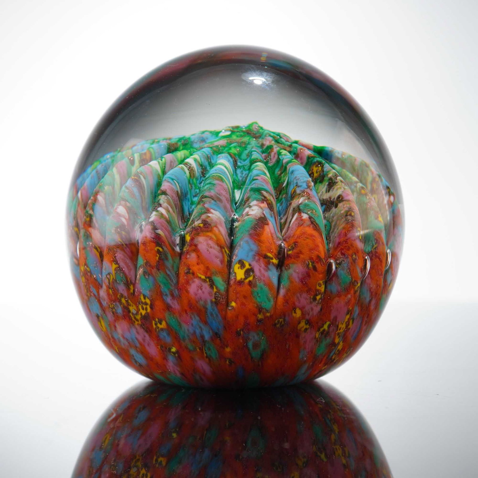 J.M. Operto Silice Creations Art Glass Paperweight: The piece features a complex internal decoration consisting of a ribbed, floral-like central motif. This internal form is created with multicolored frit in a palette dominated by vibrant shades of ora