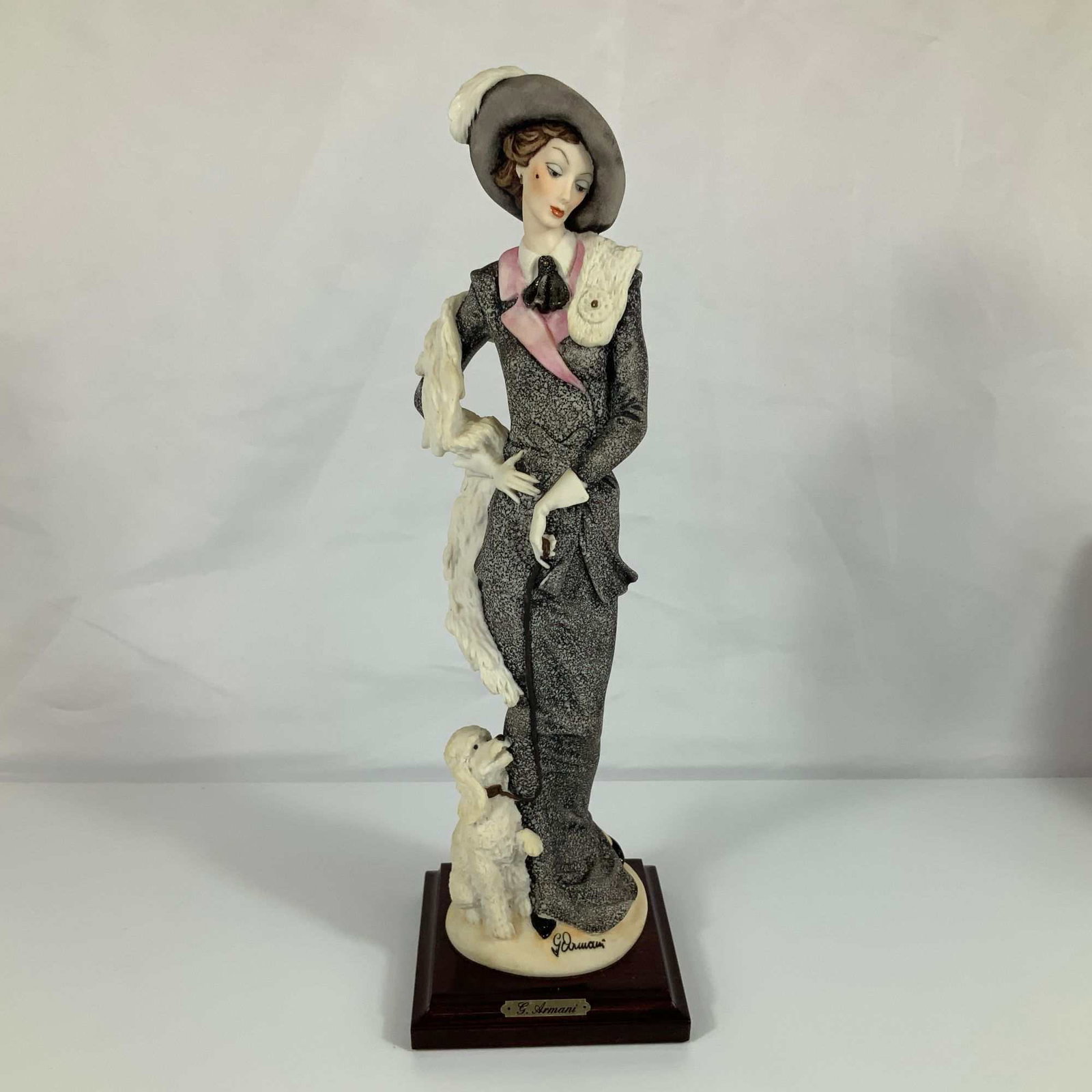 Giuseppe Armani Florence Sculture d'Arte Figurine, The Walk: Also known as "Lady with Poodle", the piece is constructed from hand-painted bisque-finish cold-cast porcelain and mounted on a square dark-finished wooden plinth. The subject is a woman dressed in ea