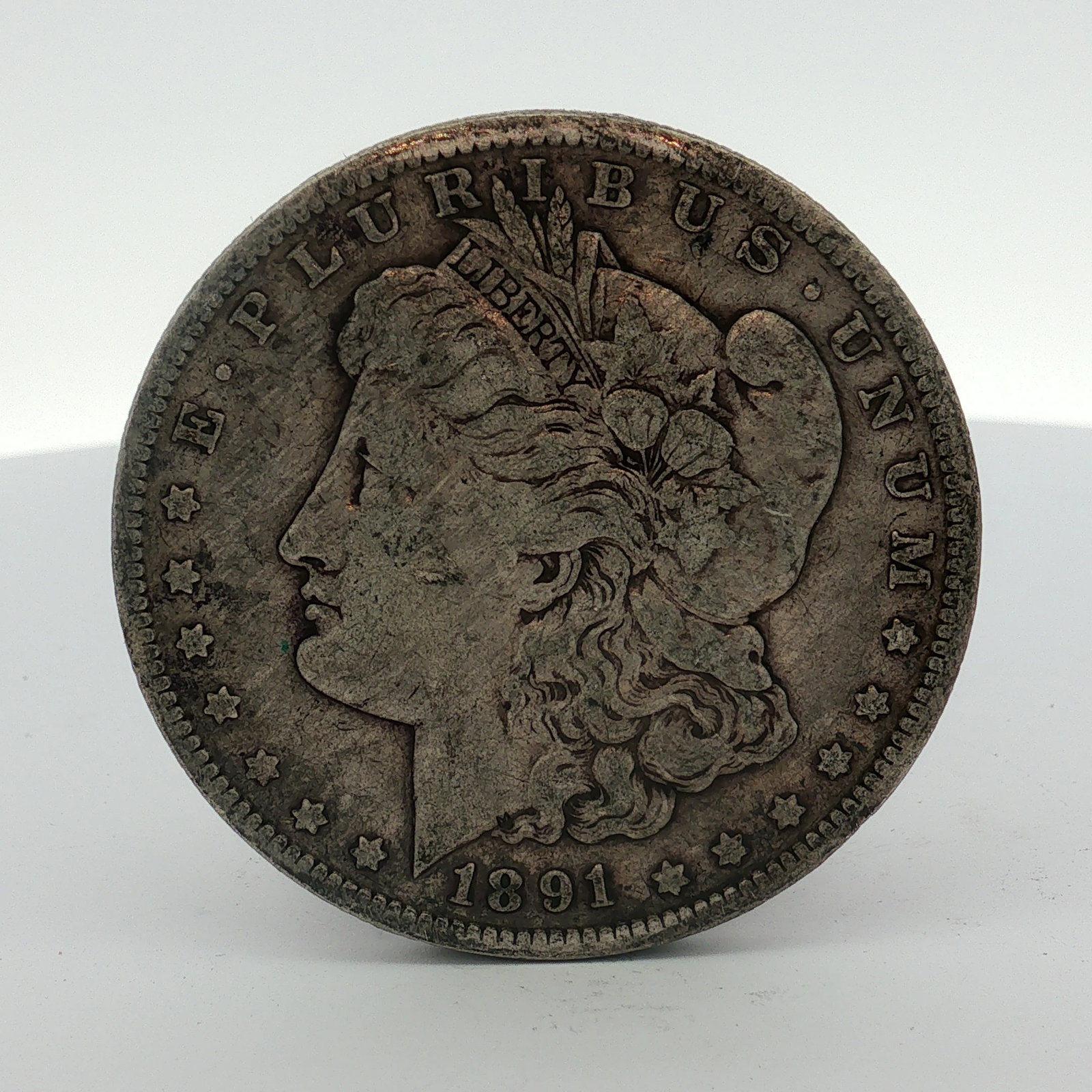 1891-O US Morgan Silver Dollar: This US Morgan silver dollar was struck at the New Orleans Mint in 1891. The coin is composed of 90% silver and 10% copper. The obverse displays the Morgan dollar design with the legend E PLURIBUS UNU